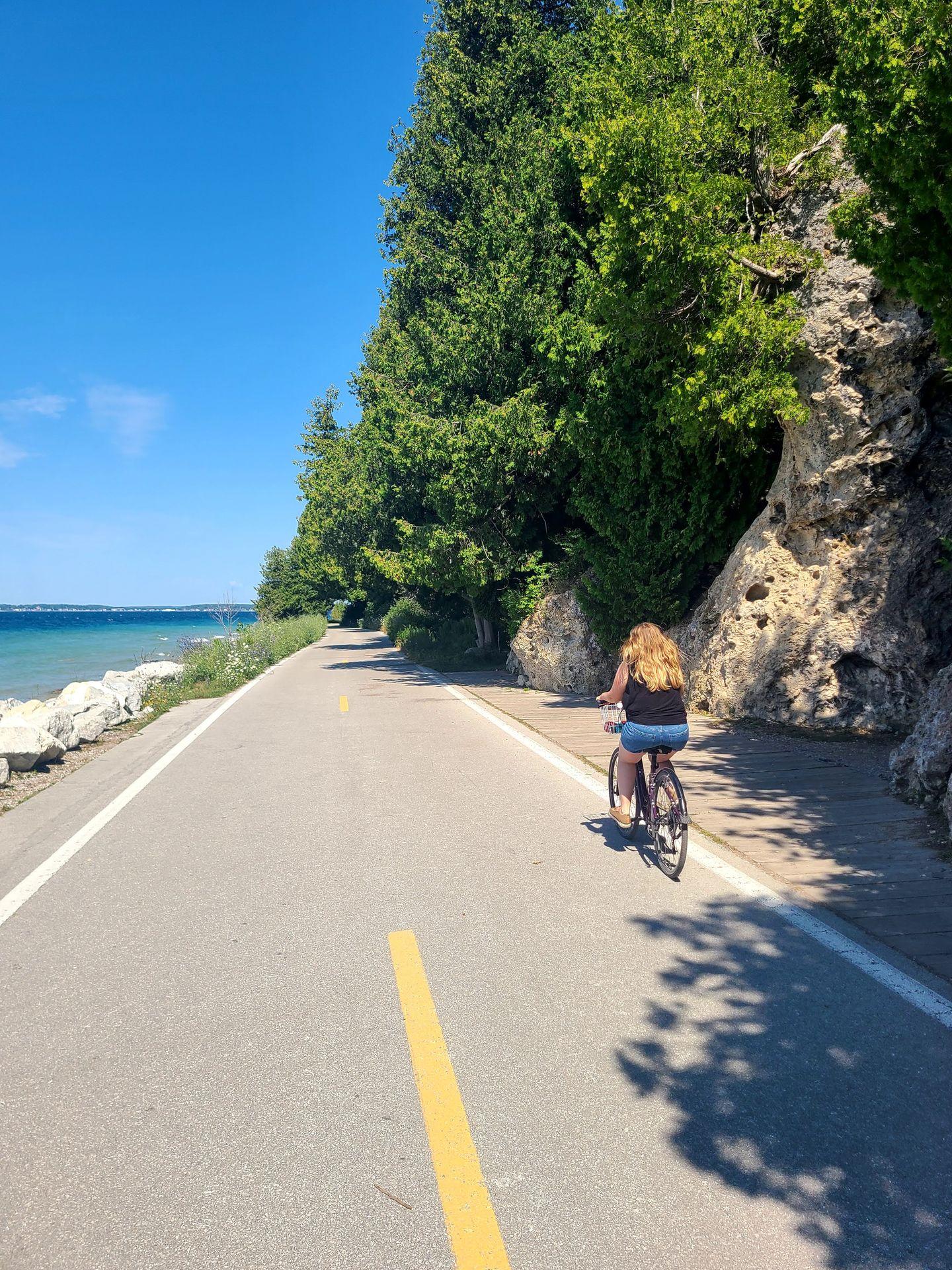 Lydia biking along a paved path on Mackinac Island.