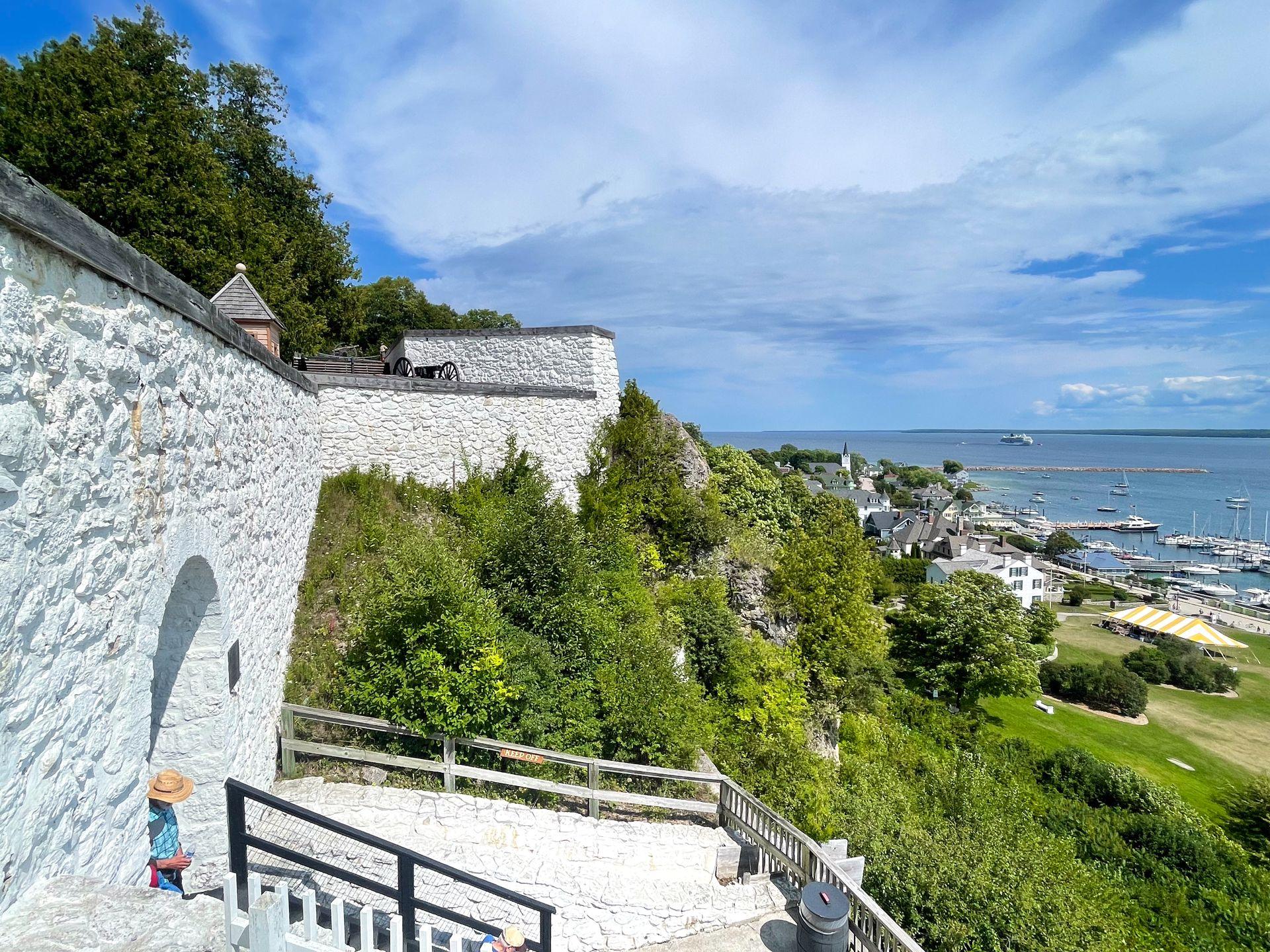 A white fort up on a hill overlooking Downtown Mackinac.