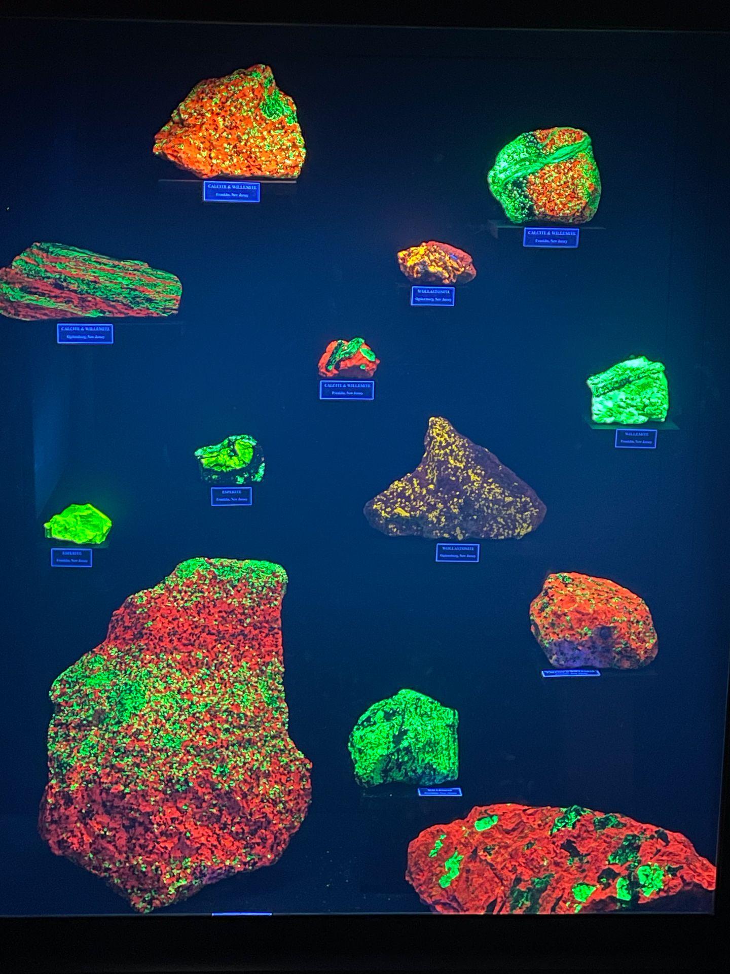 A collection of rocks glowing green and red in fluorescent light