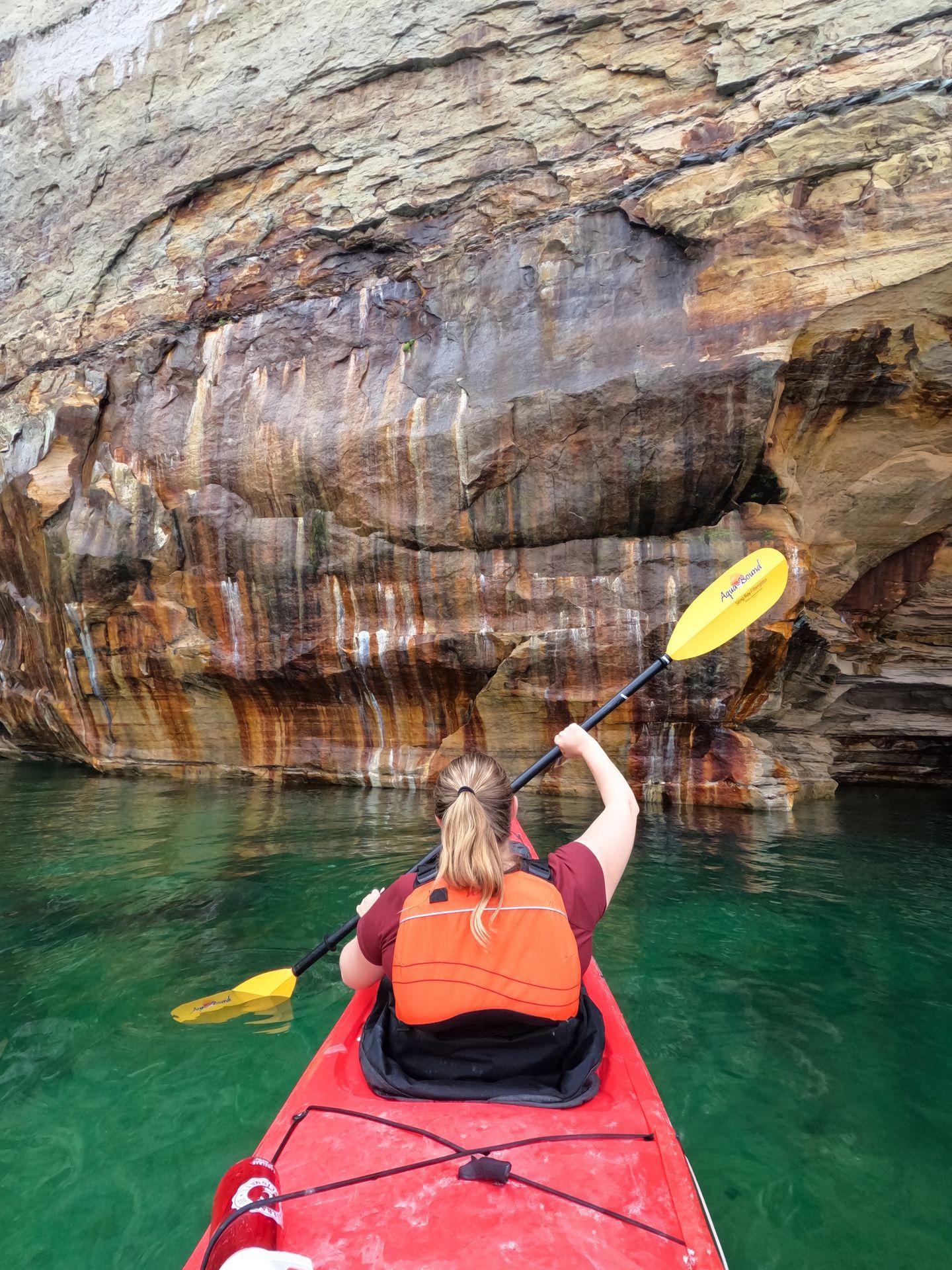Lydia kayaking towards a wall that looks as if it is painted