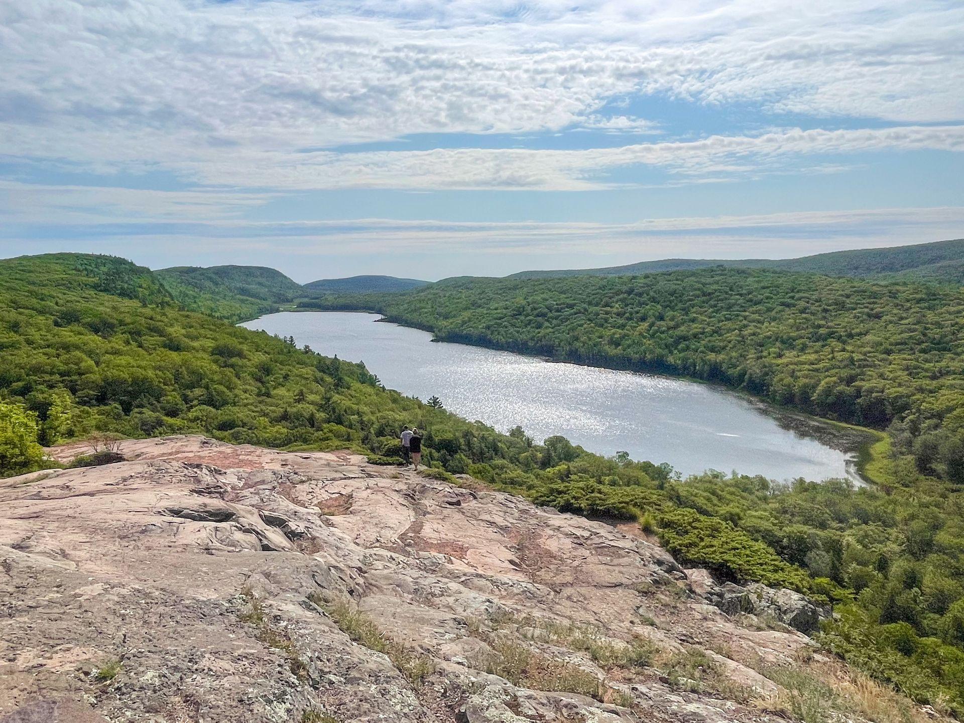 A lake surrounded by trees seen from a rocky area on the Escarpment Trail