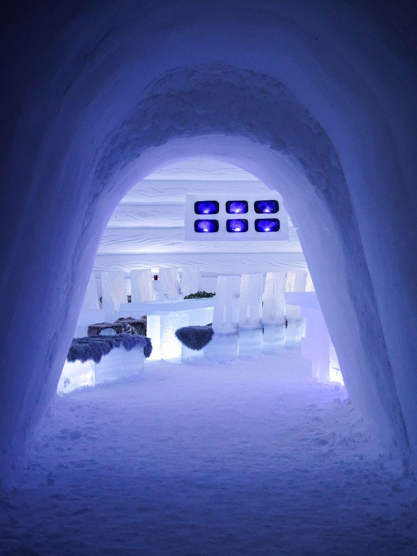 Looking through a snowy arch into a dining area made entirely of ice