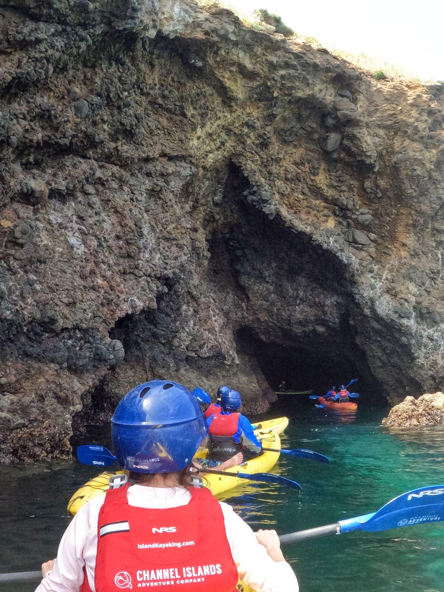 A line of kayaks heading into a sea cave