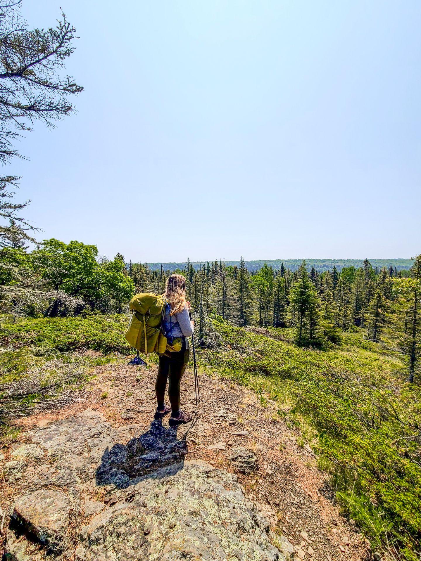 Lydia hiking and wearing a backpack on Isle Royale