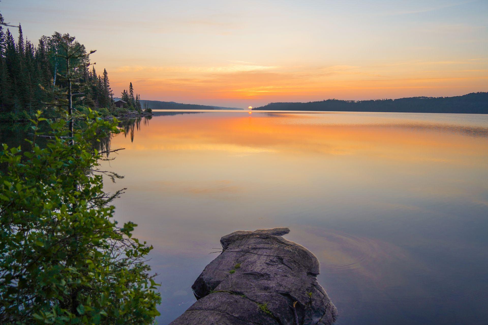 Watching the sunrise from a Moskey Basin campsite in Isle Royale. There is a rock extends out into the water at the center of the photo.