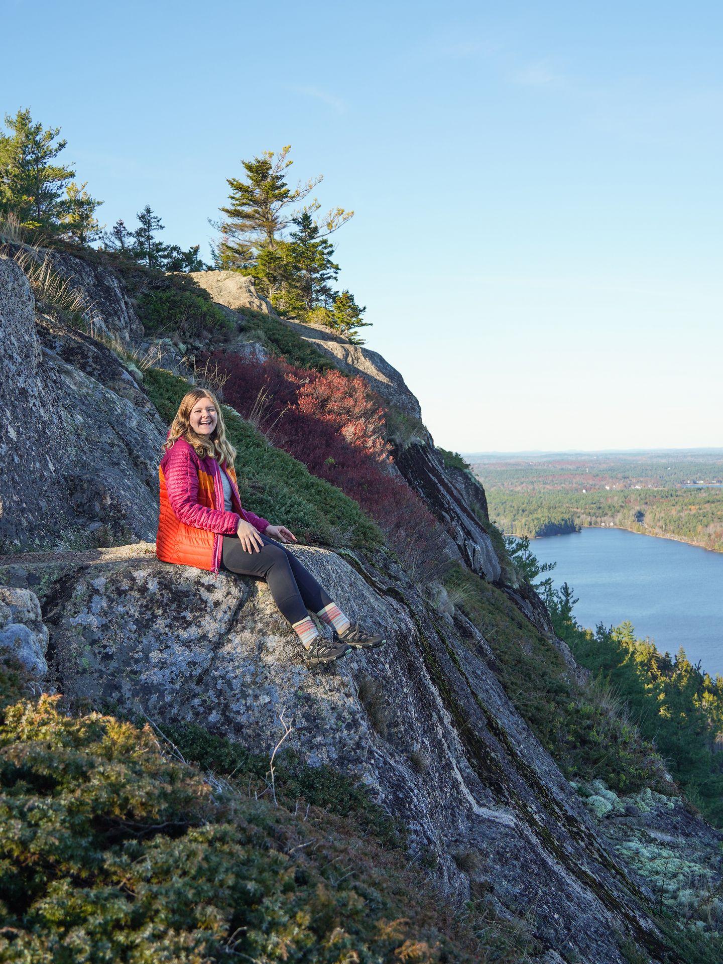 Lydia sitting on the edge of a cliff on a hike in Maine.
