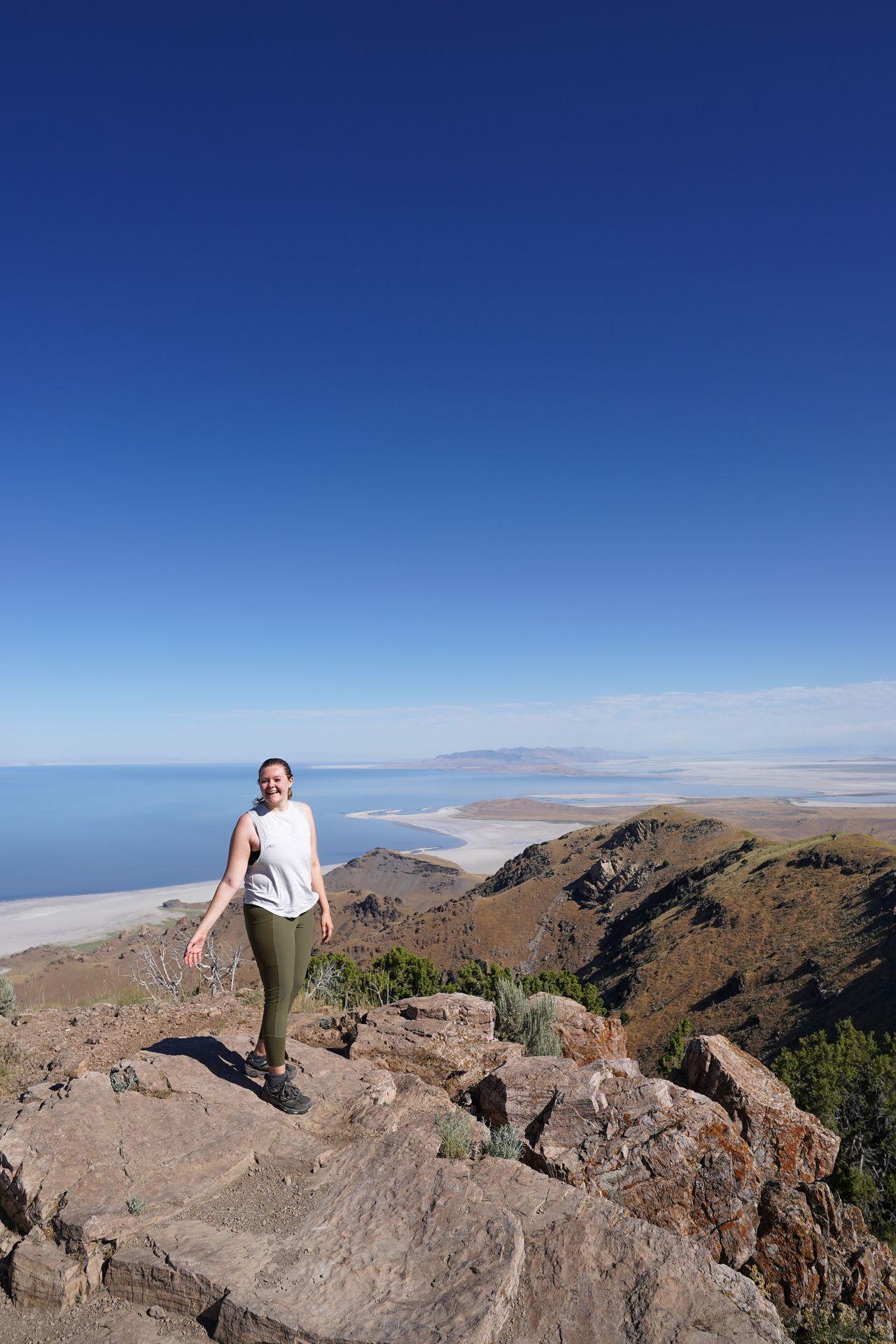 Lydia standing on top of a mountain peak wearing green leggings