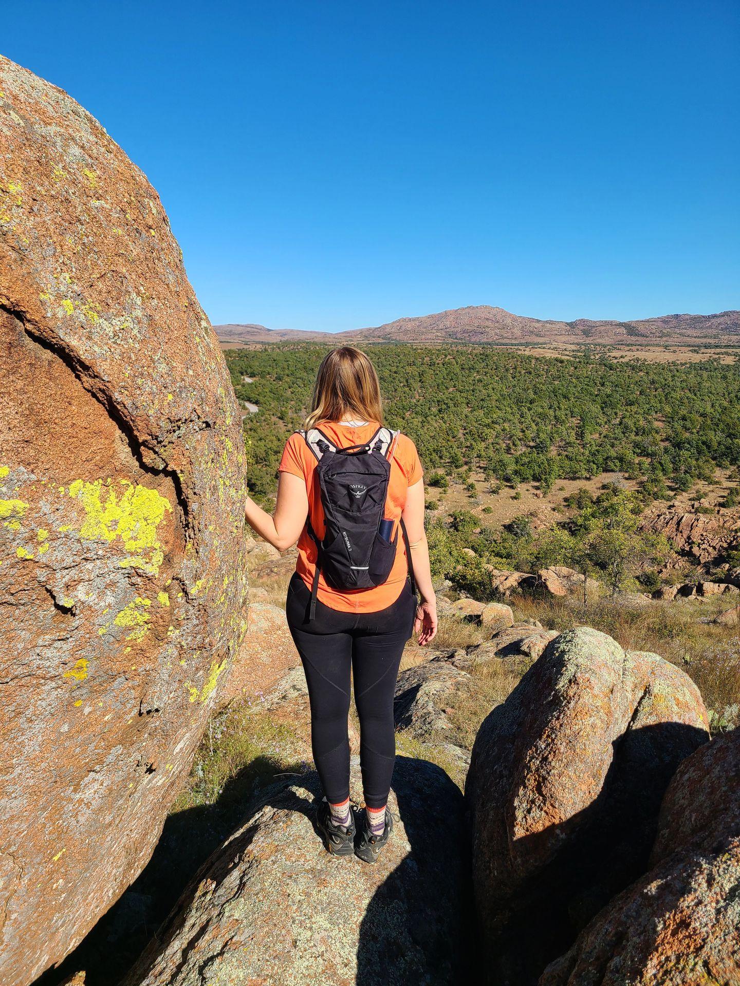 Lydia with her back to the camera looking out at a view on a trail in the Wichita Mountains, Oklahoma.