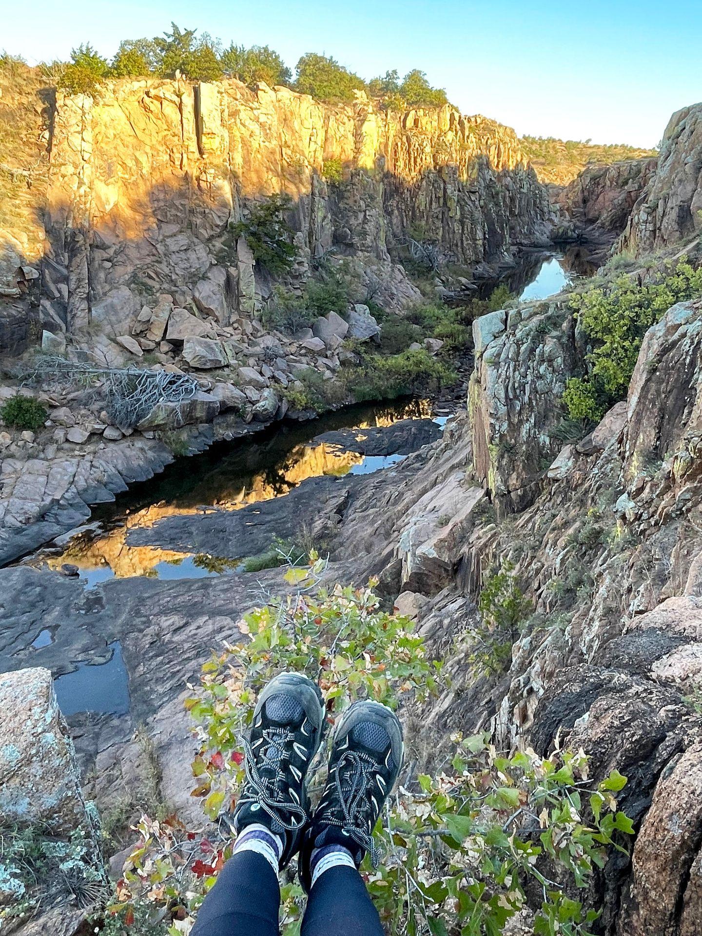 A photo of Lydia's feet wearing Merrell hiking shoes. In the background is a small canyon in Wichita Falls, Oklahoma.