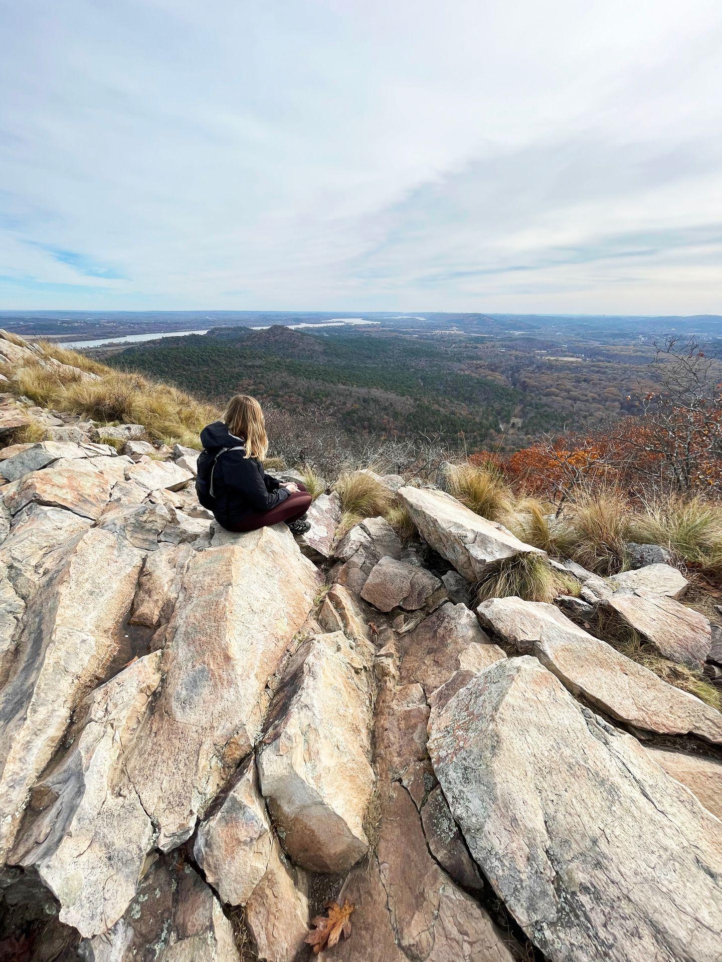 Lydia sitting on a rocky mountain top at Pinnacle Mountain State Park