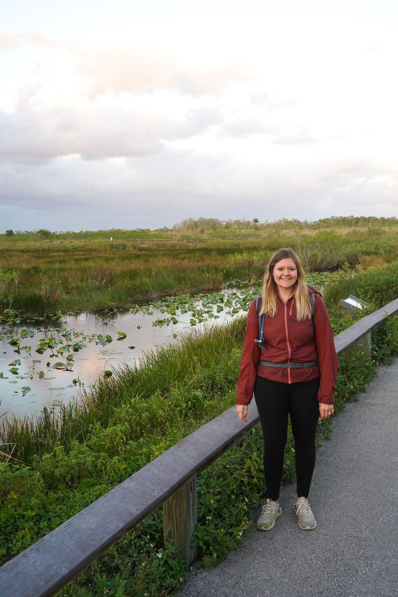 Lydia wearing a red jacket next to water and a swamp in Florida