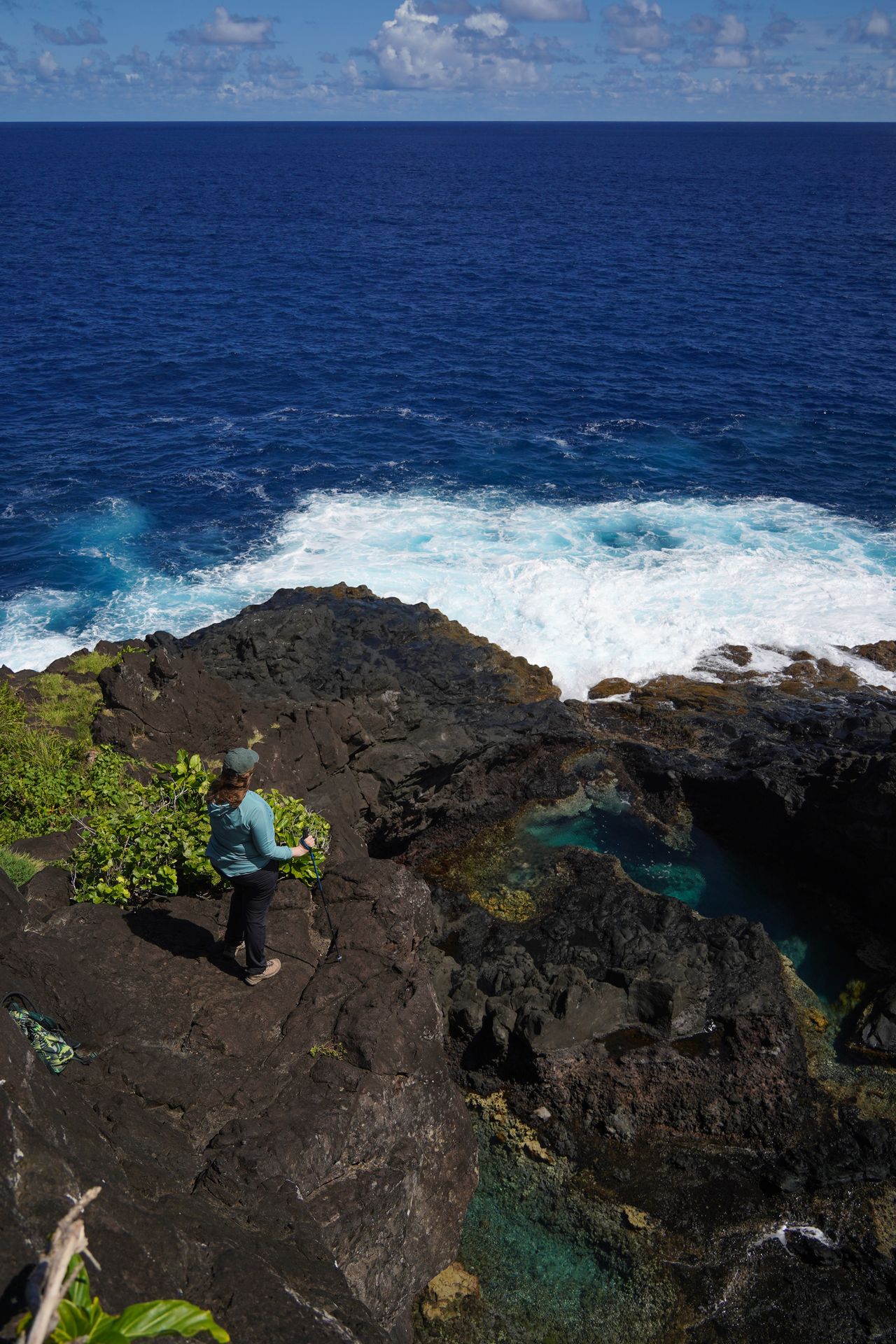 Lydia standing on a black, rocky coast on the Lower Sauma Ridge Trail