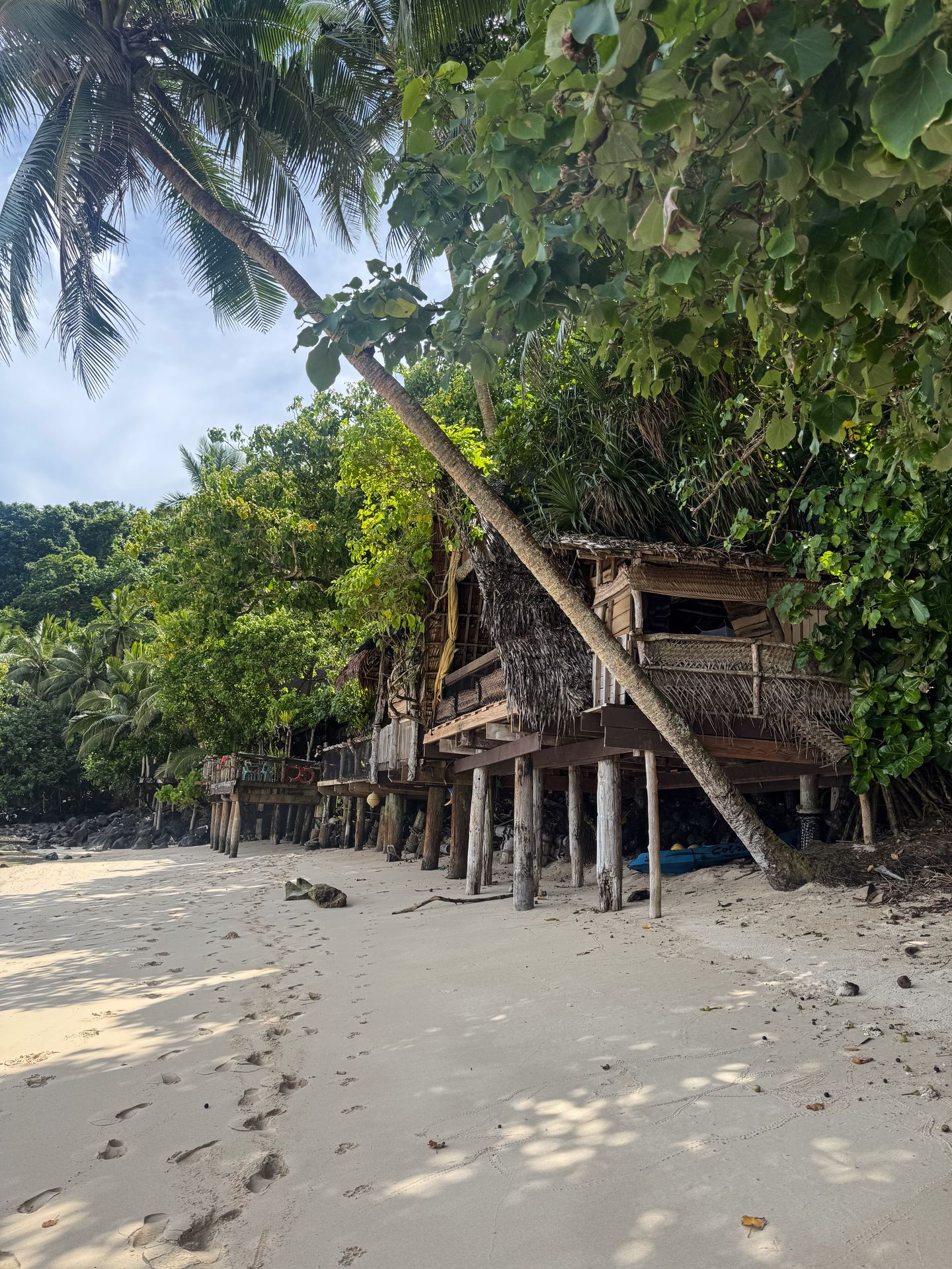 A wooden building on stilts along a white sand beach