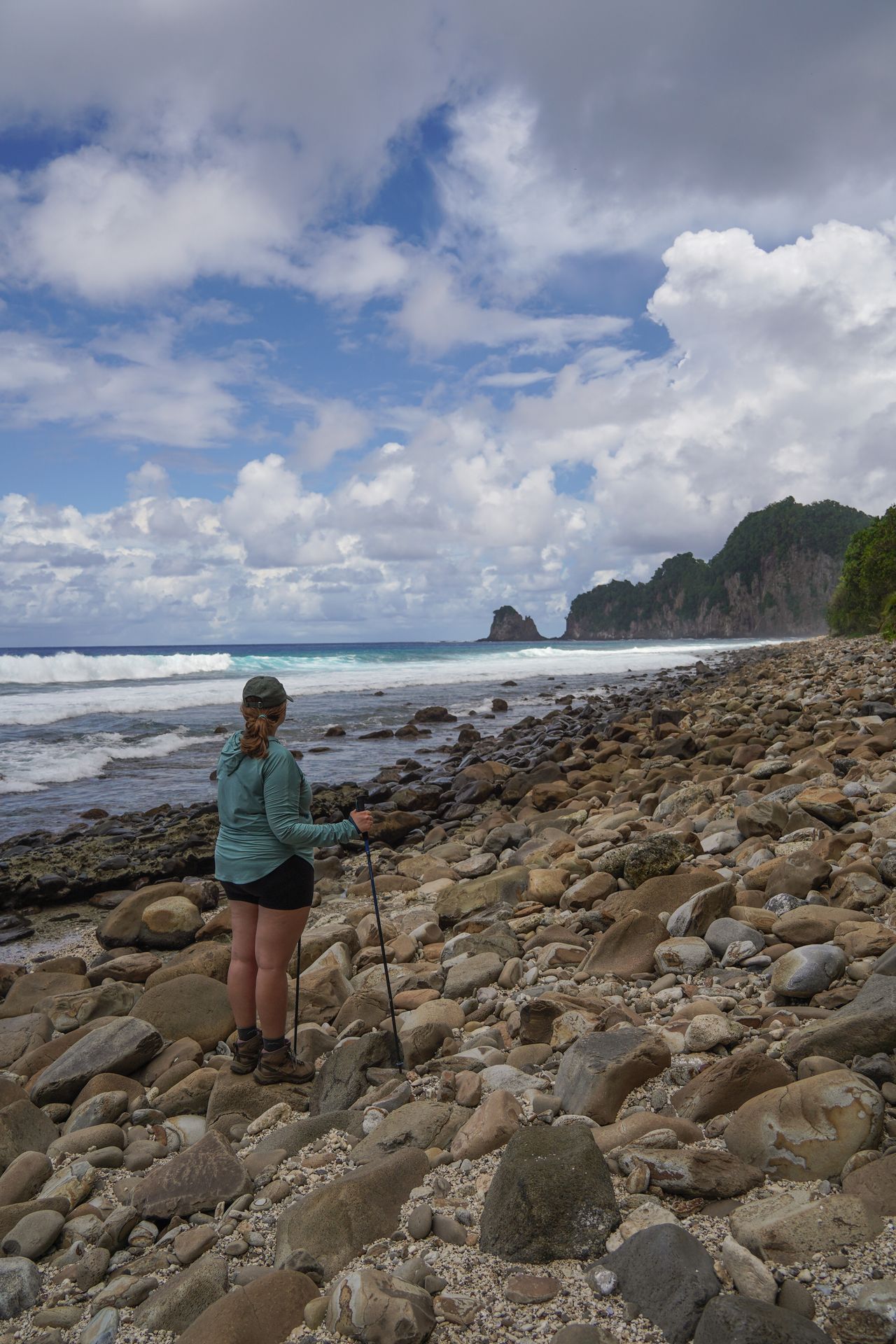 Lydia standing on a rocky beach at the viewpoint of the Tuafanua Trail