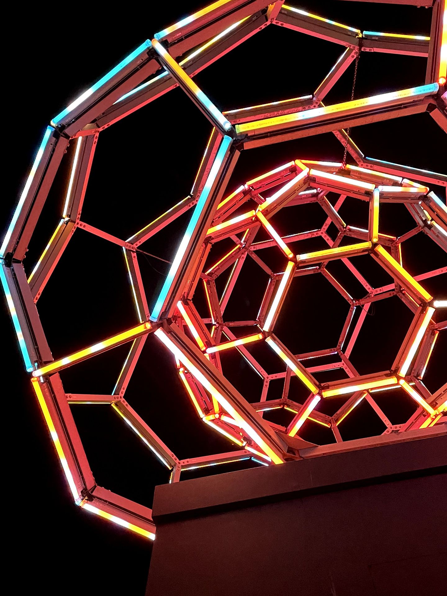 A giant ball made up of red, yellow and blue neon lights.