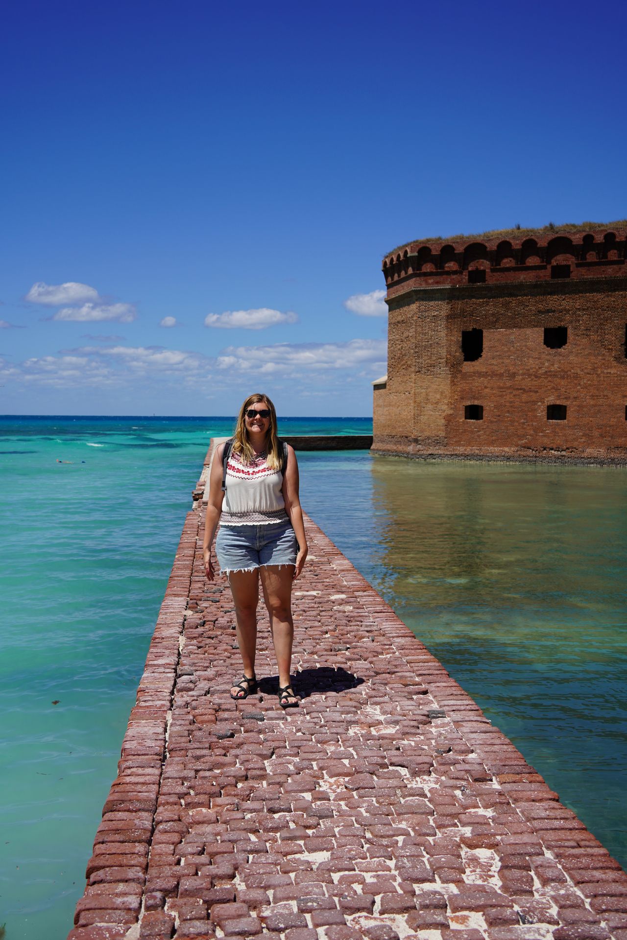 Lydia standing on a moat wall made of bricks at Dry Tortugas
