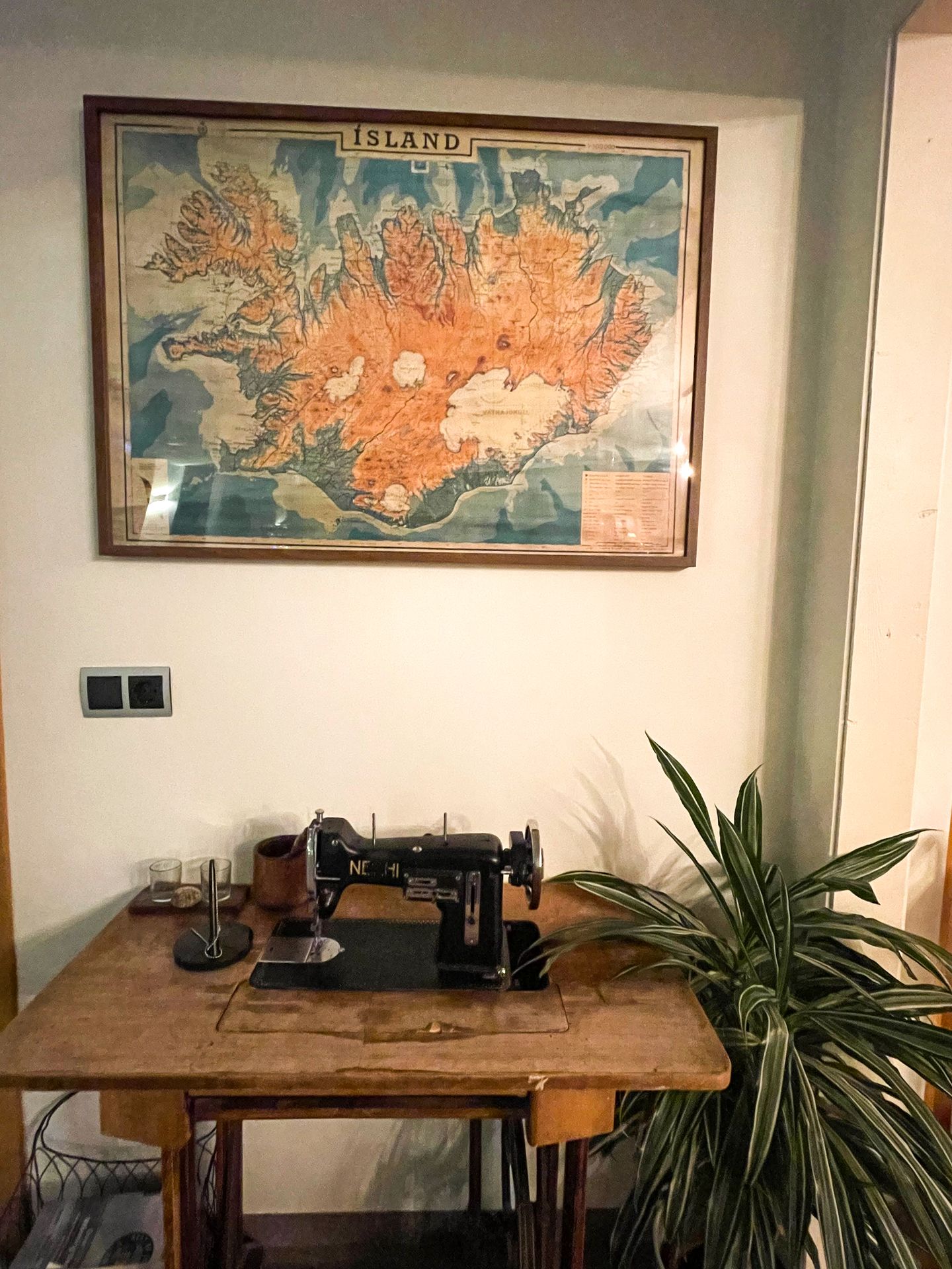 A vintage sewing machine with a map on the wall in the Héraðsskólinn Historic Guesthouse