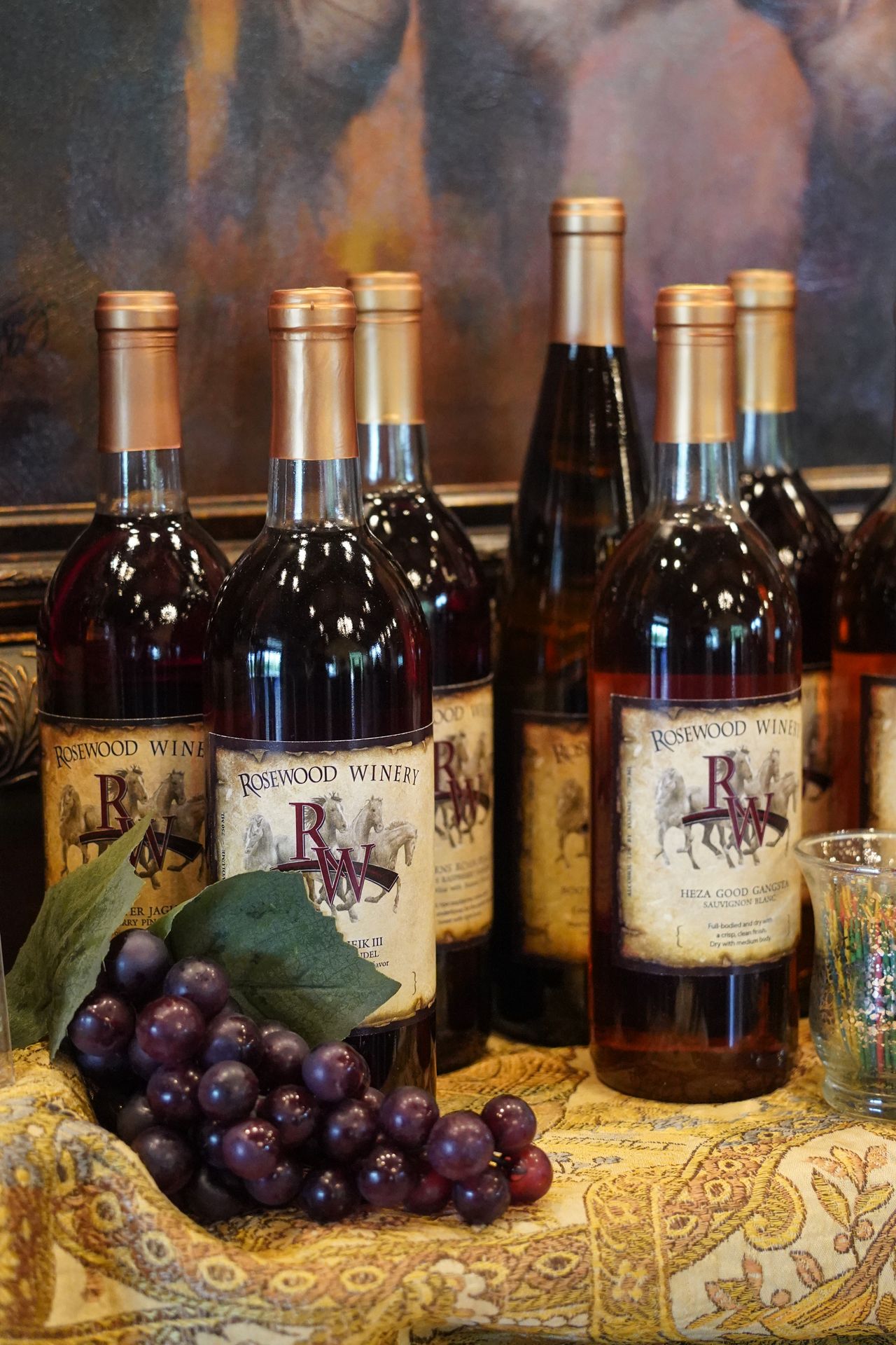 Several bottles of wine next to red grapes at the Rosewood Winery