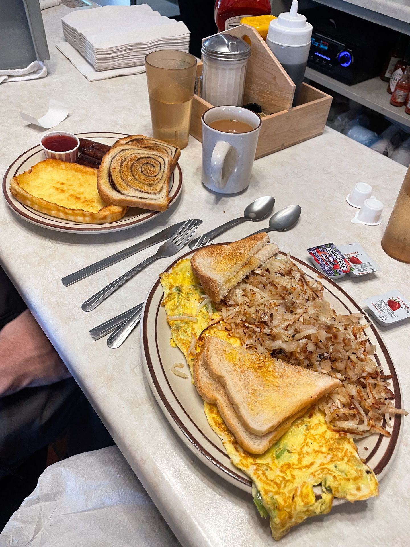 Two plates of breakfast food from Suomi Home Bakery & Restaurant. There is scrambled eggs, toast, hashbrowns and Finnish pastries.