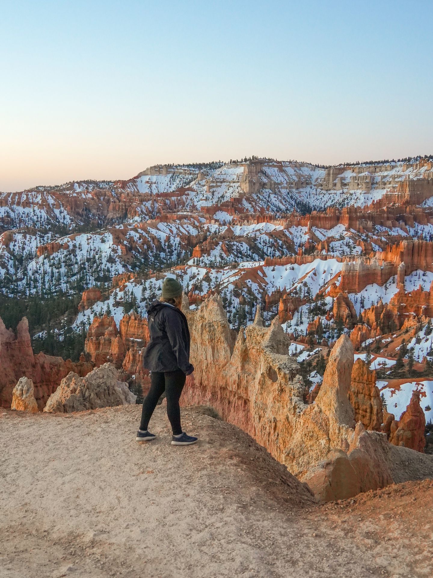 Lydia looking out at hoodoos covered in snow during sunrise at Bryce Canyon