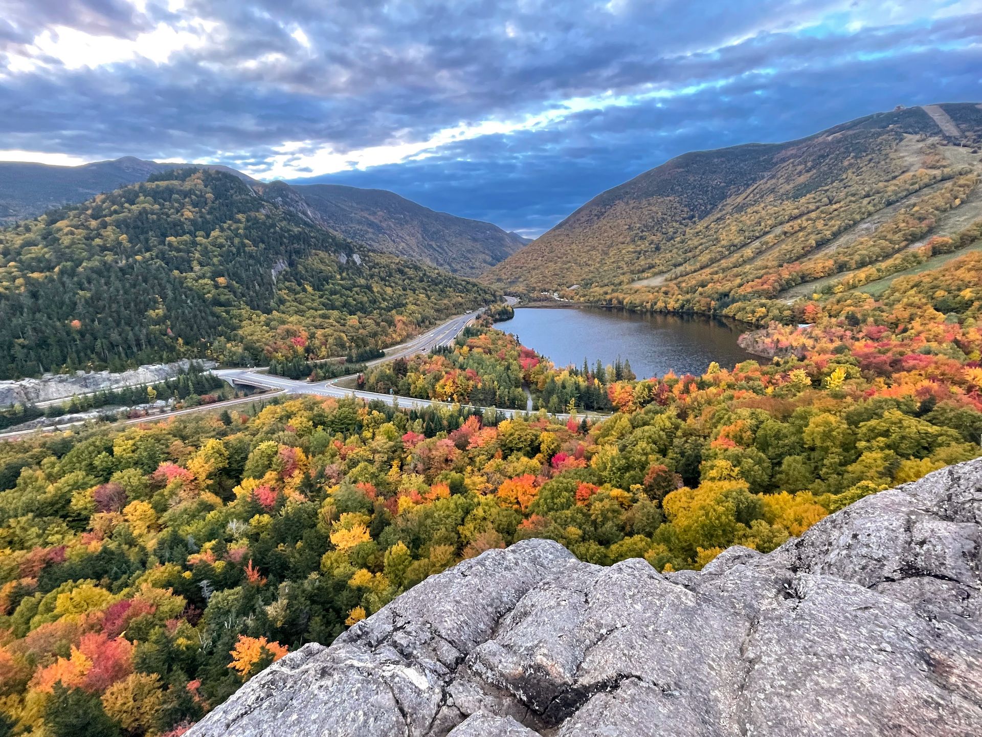 The view of Artist's Bluff. There is a lake surrounded by mountains and colorful fall foliage.