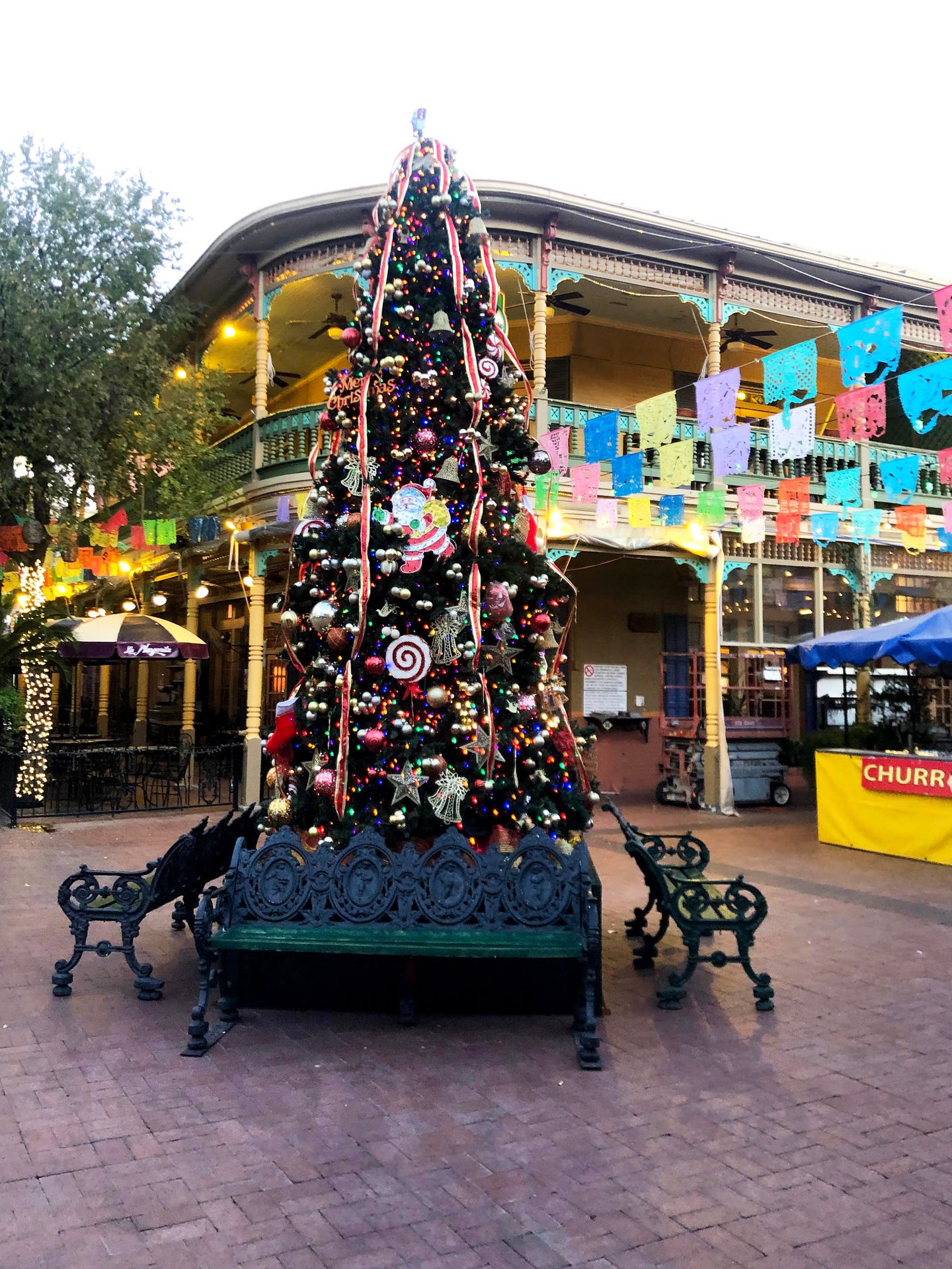 A Christmas tree with colorful flags in the background.