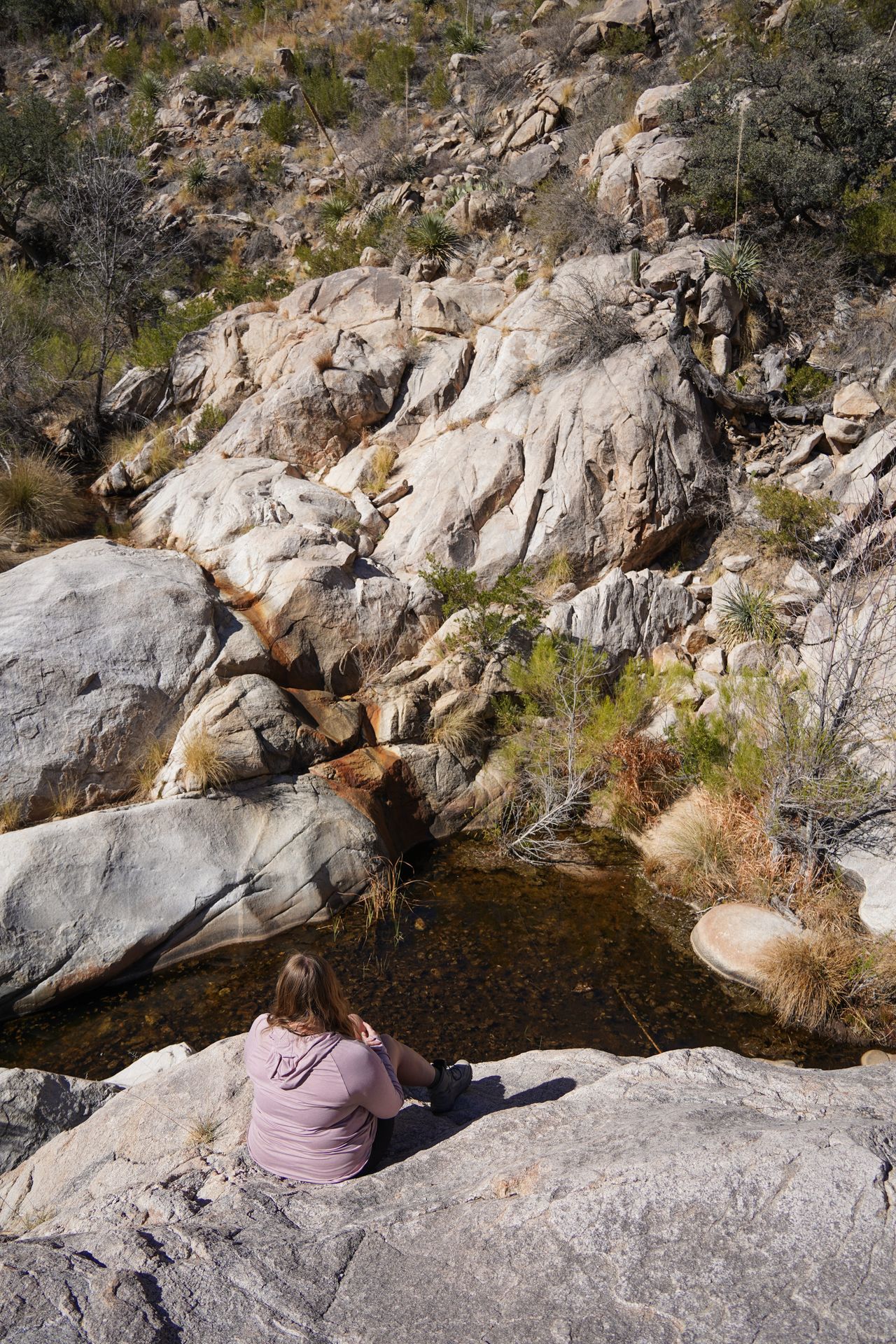 Lydia sitting on white rocks above a pool of water