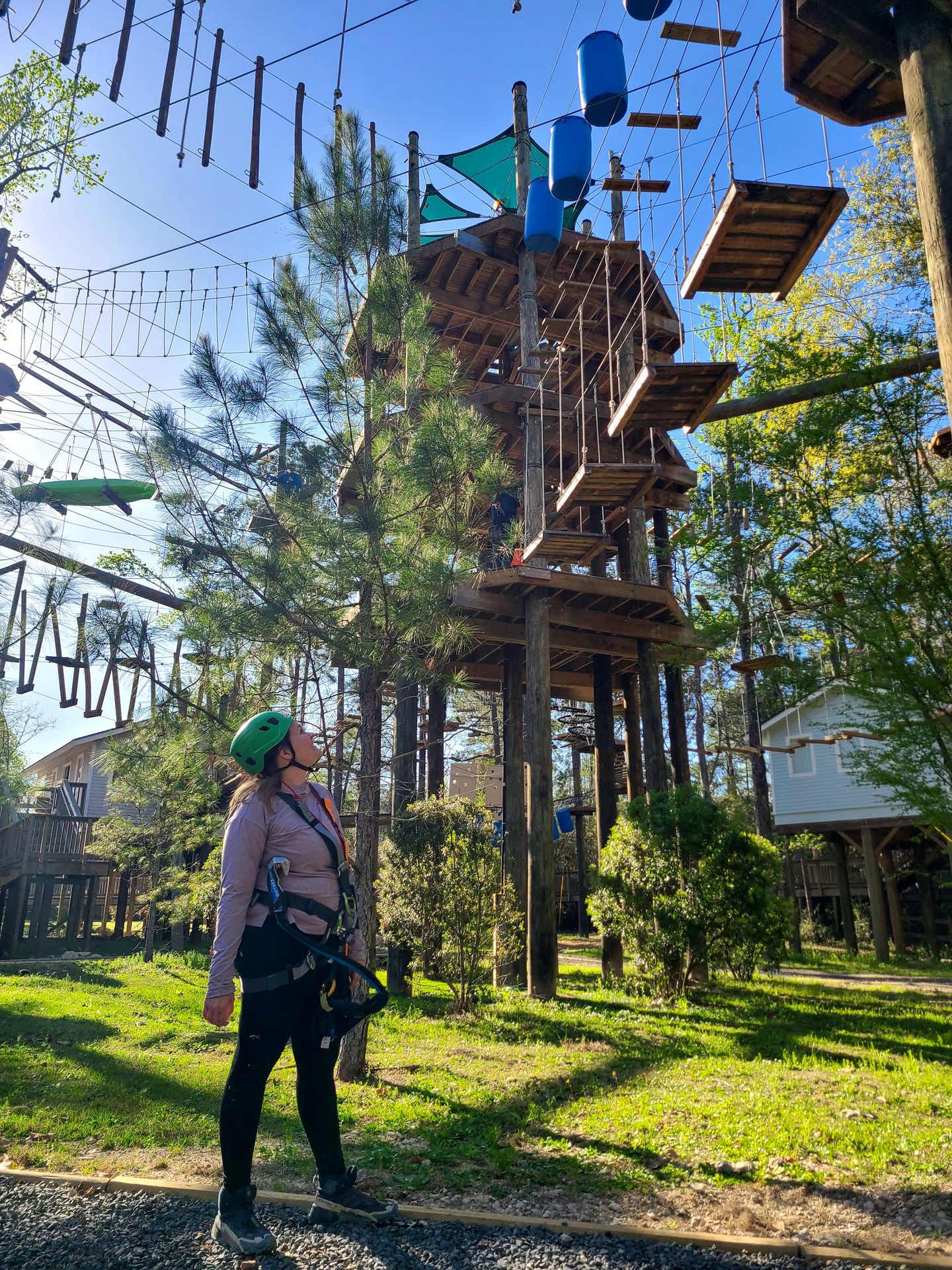 Lydia looking up at the Texas TreeVentures course wearing a harness and helmet