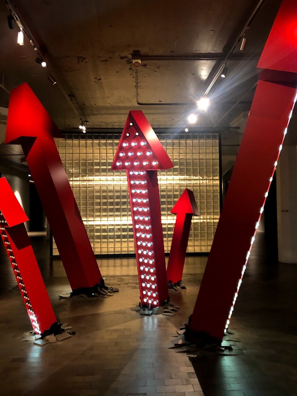 Several giant red arrows sticking up out of the ground with lights on them.