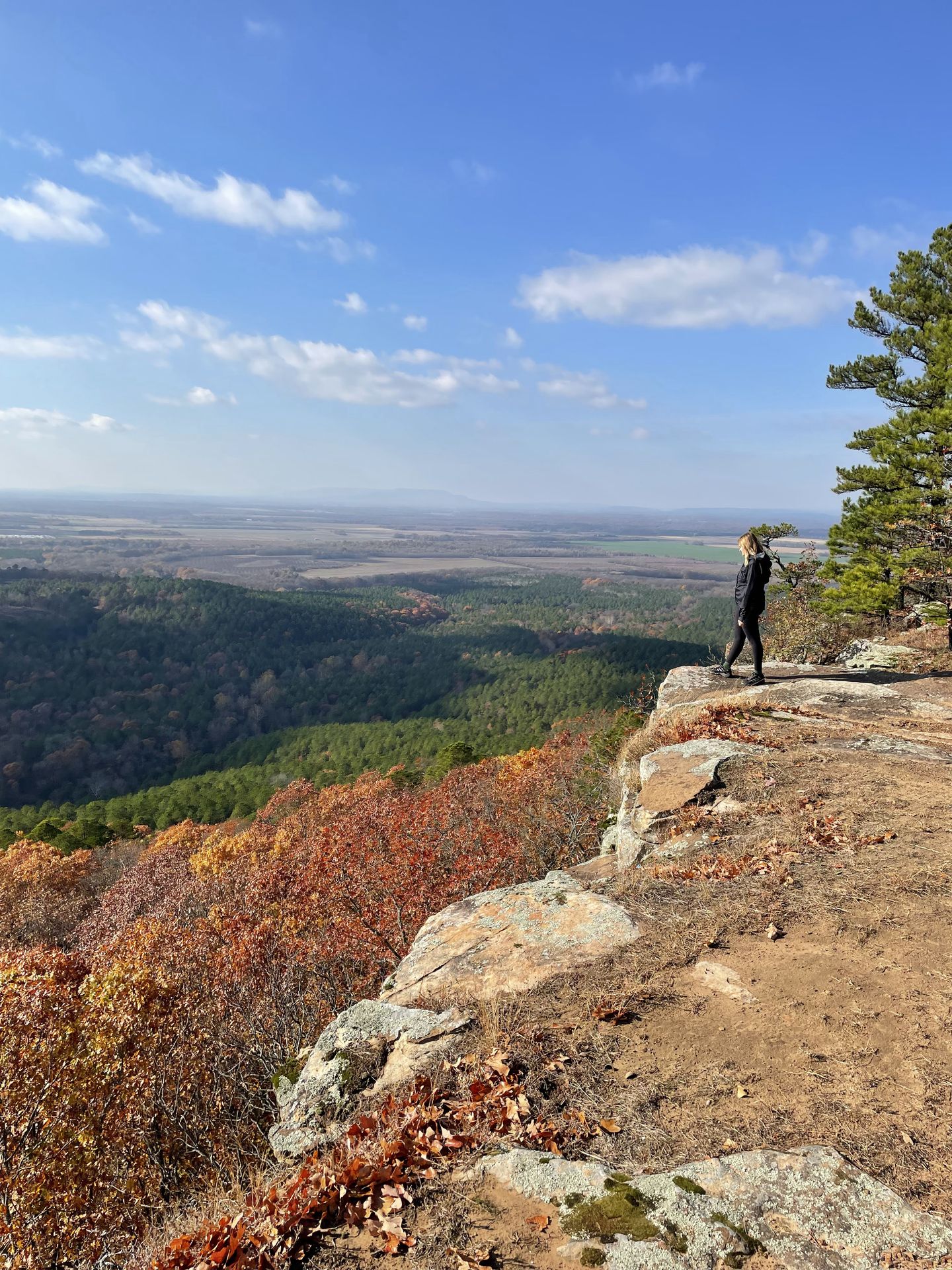 Lydia standing at the edge of a cliff with a view of the valley below.