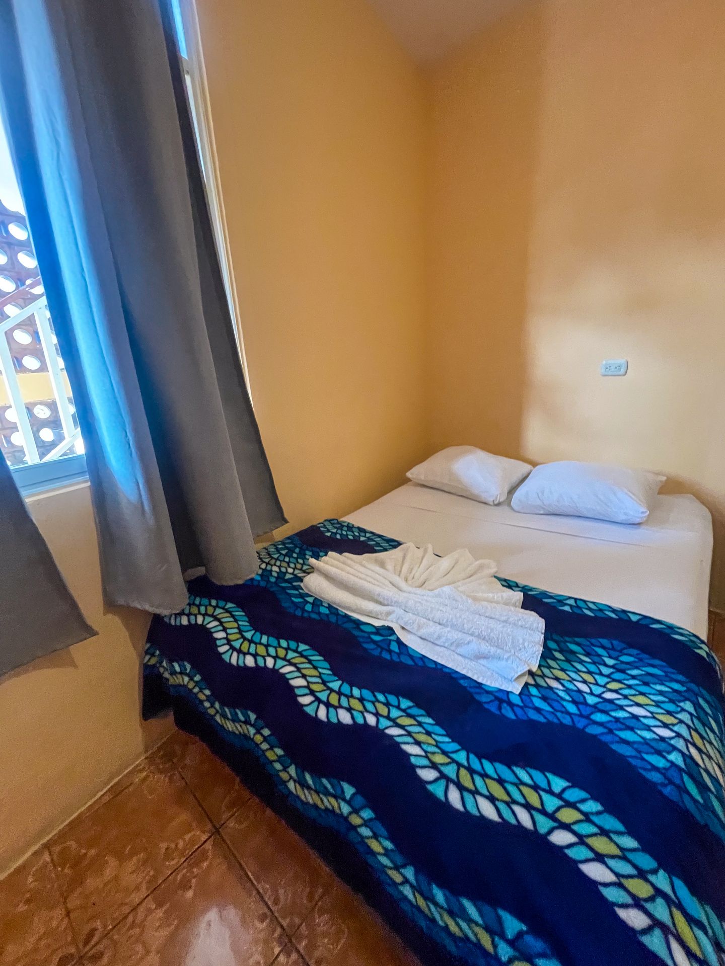 The room at Hotel Amigos, which has yellow walls and a bed with a blue blanket