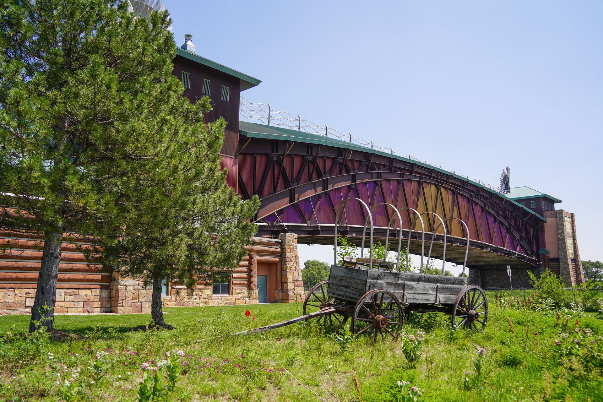 The Archway Museum, which goes over I-80. There is an old wooden wagon among greenery in front of the museum.