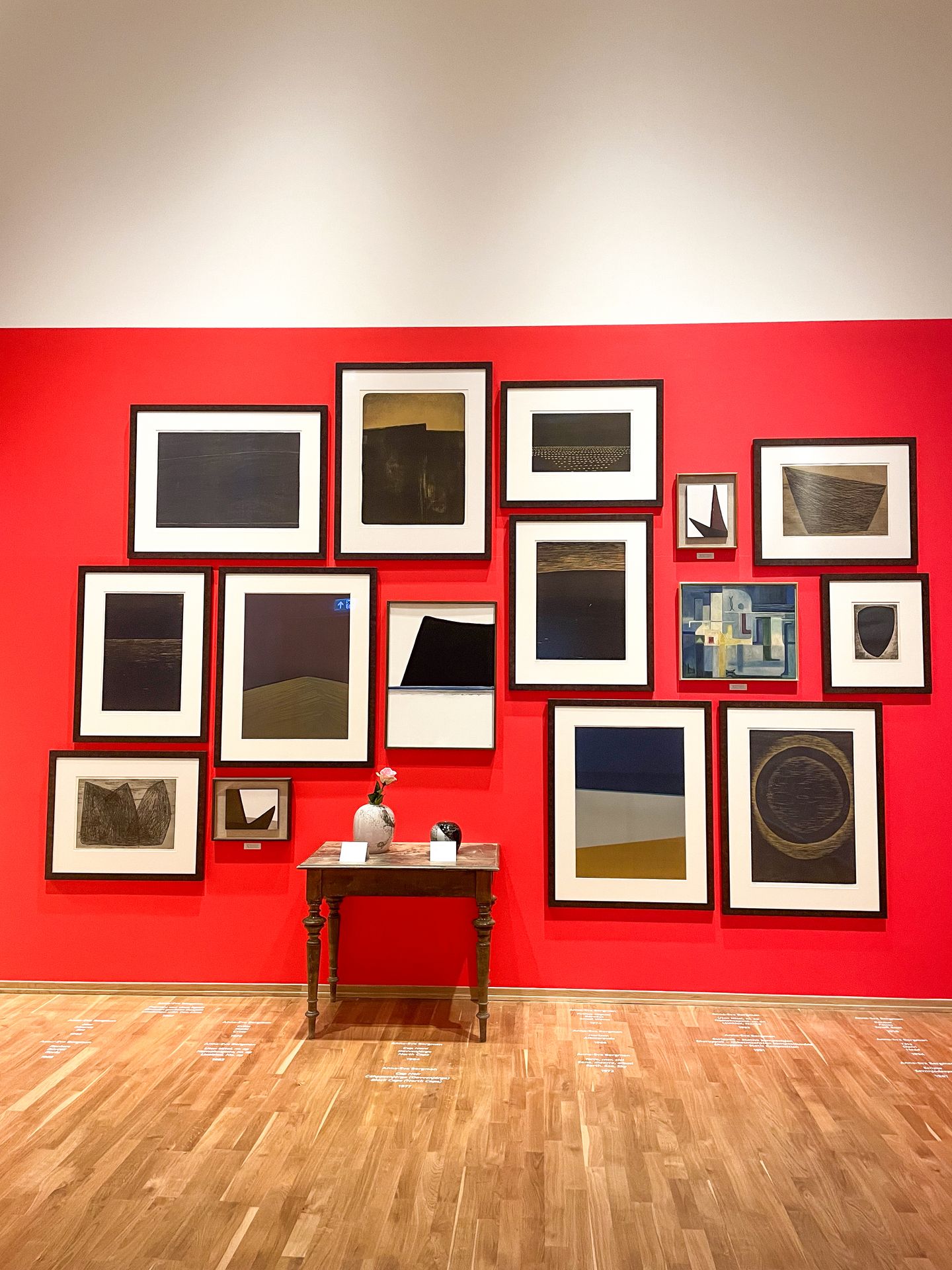 A red wall with a variety of abstract artwork arranged on it