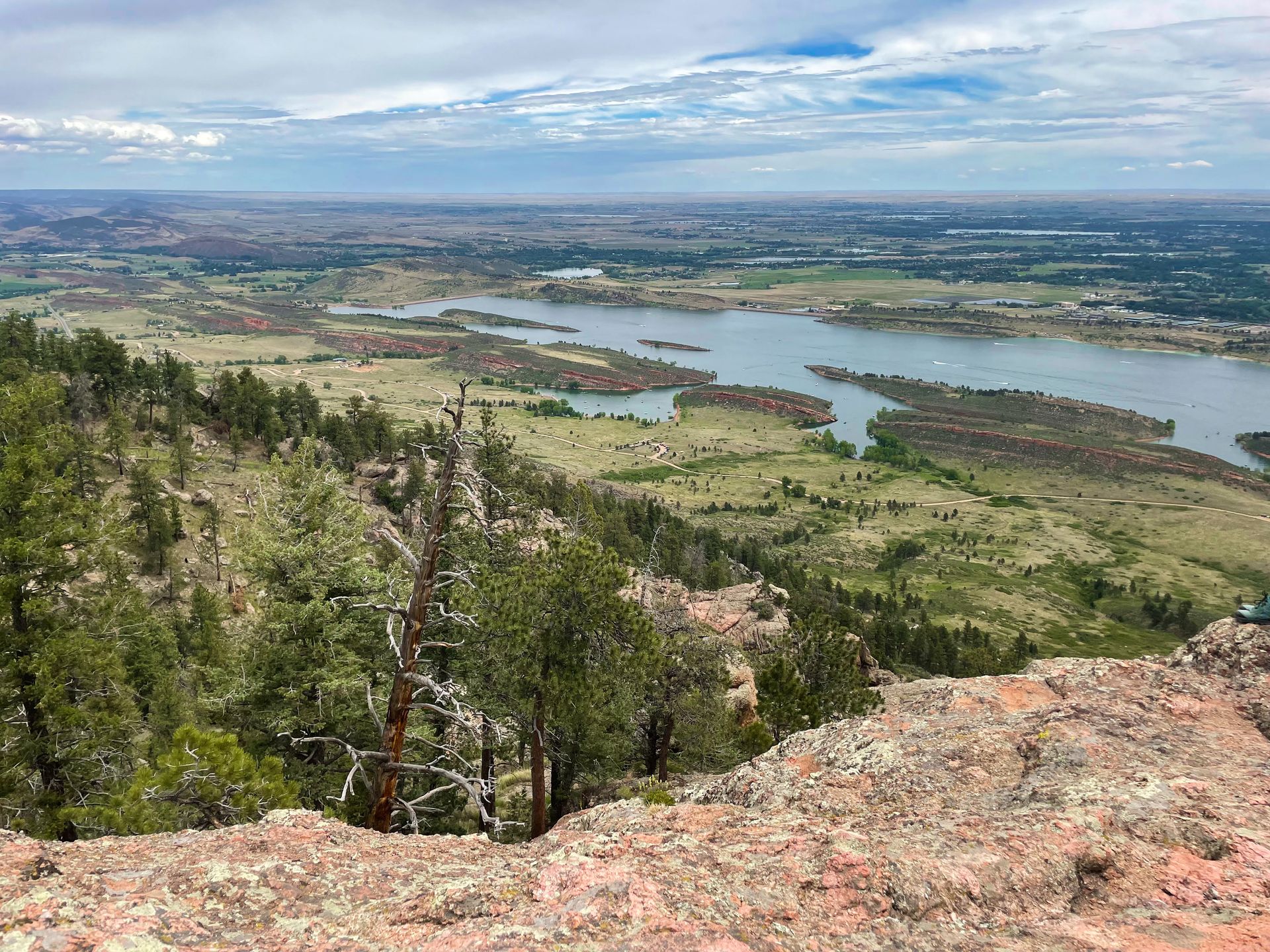 A view looking down at a valley with a large reservoir full of blue water. There are many green trees in the distance.