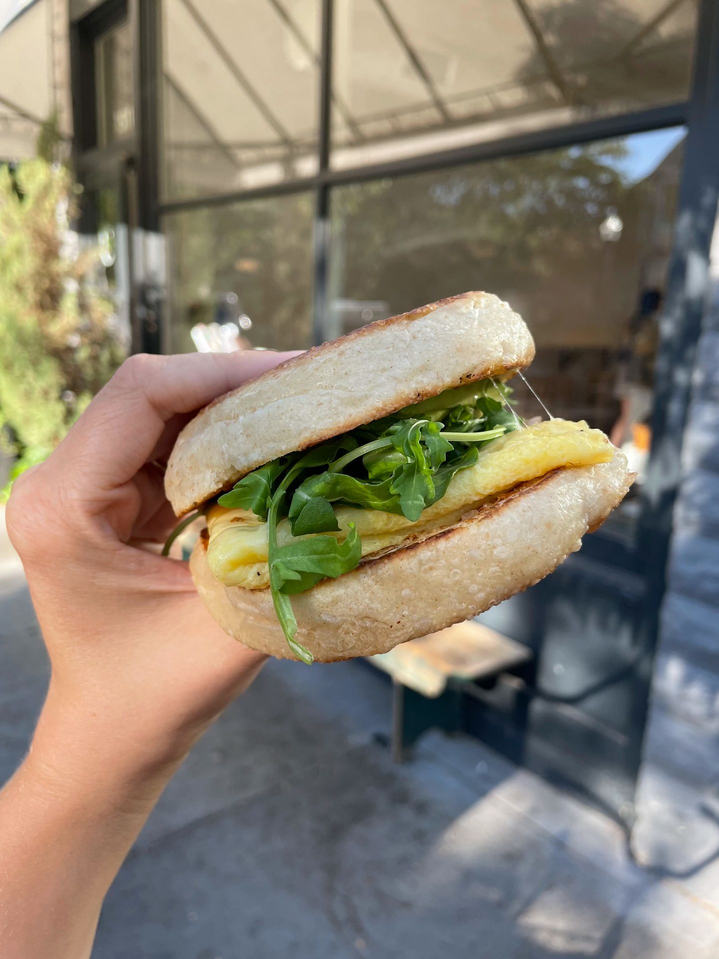 Holding up a breakfast sandwich on an english muffin from Certified Kitchen and Bakery.