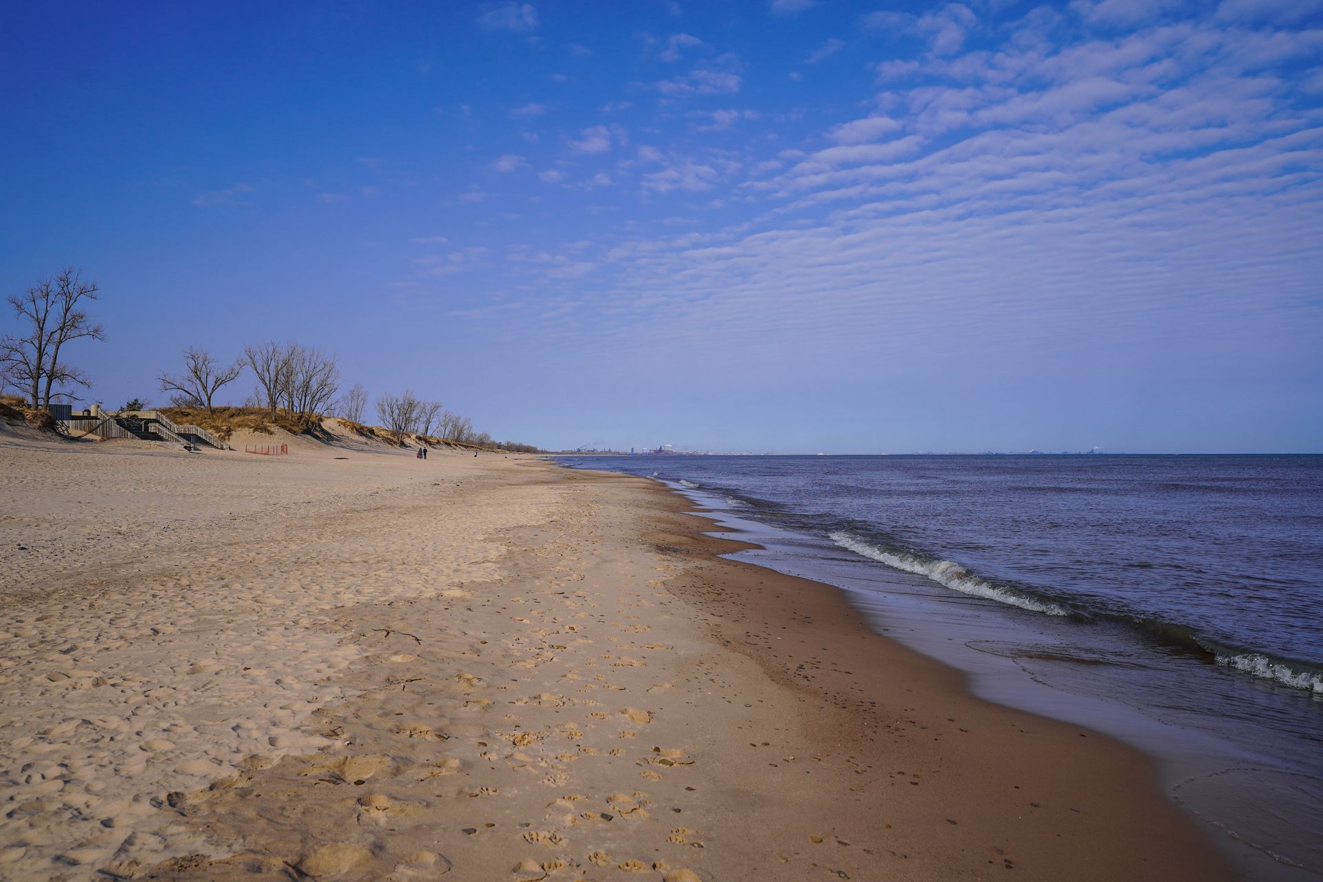 A sandy beach with some industry in the distance