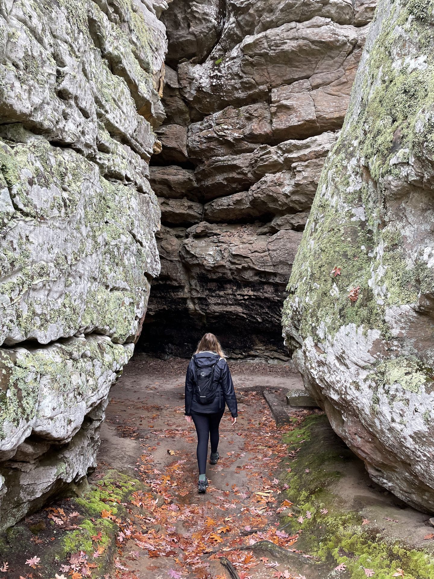 Lydia walking away between some tall rock faces on the Bear Cave trail.