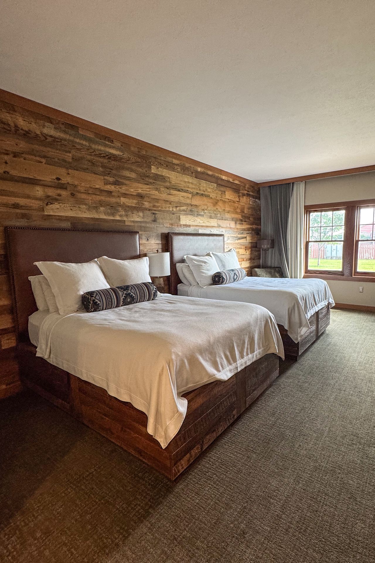 A room with two beds and a wood paneled wall in the Norfolk Lodge and Suites