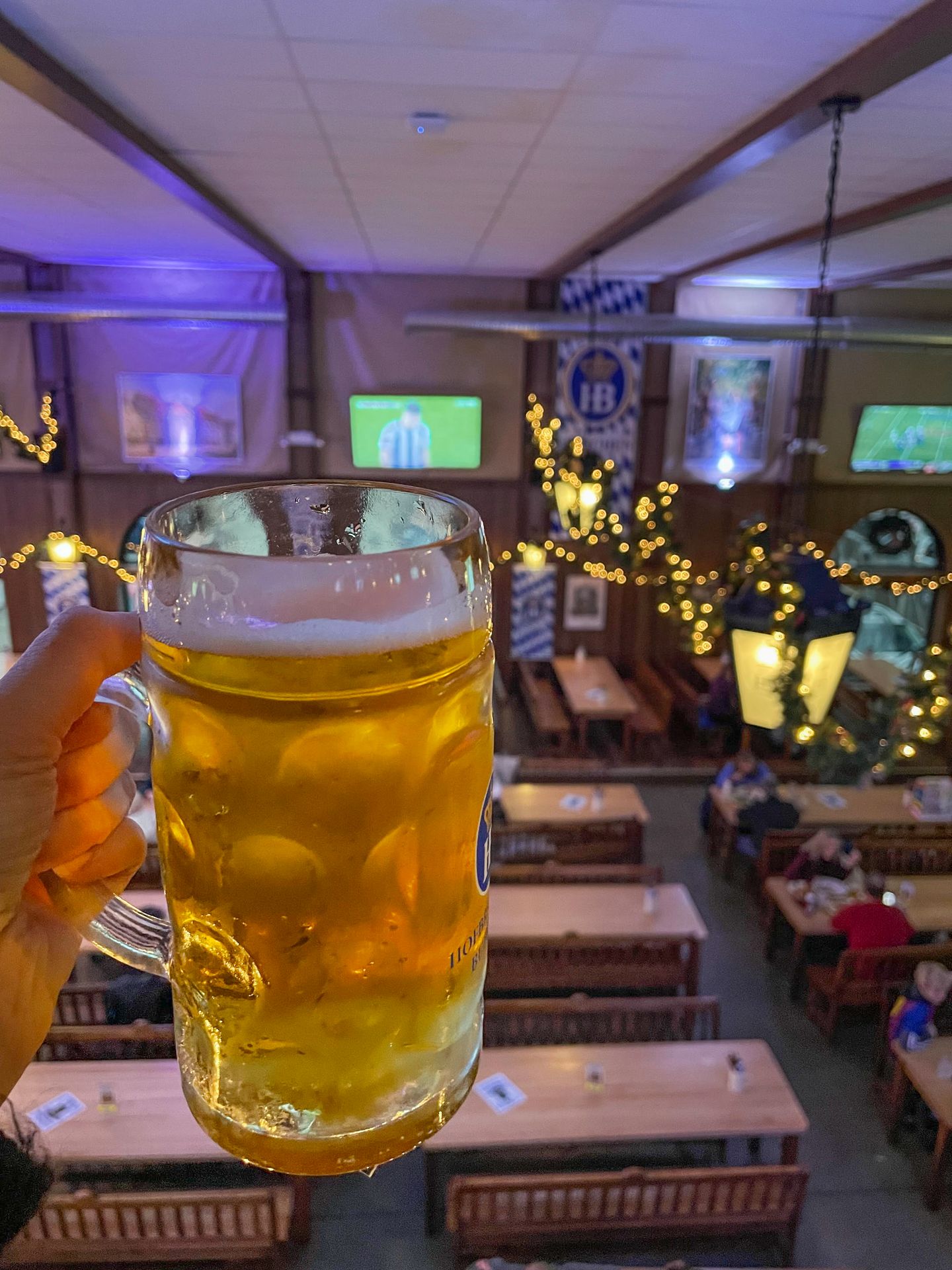 Holding up a tall stein of beer from the second floor inside of the Hofbrauhaus