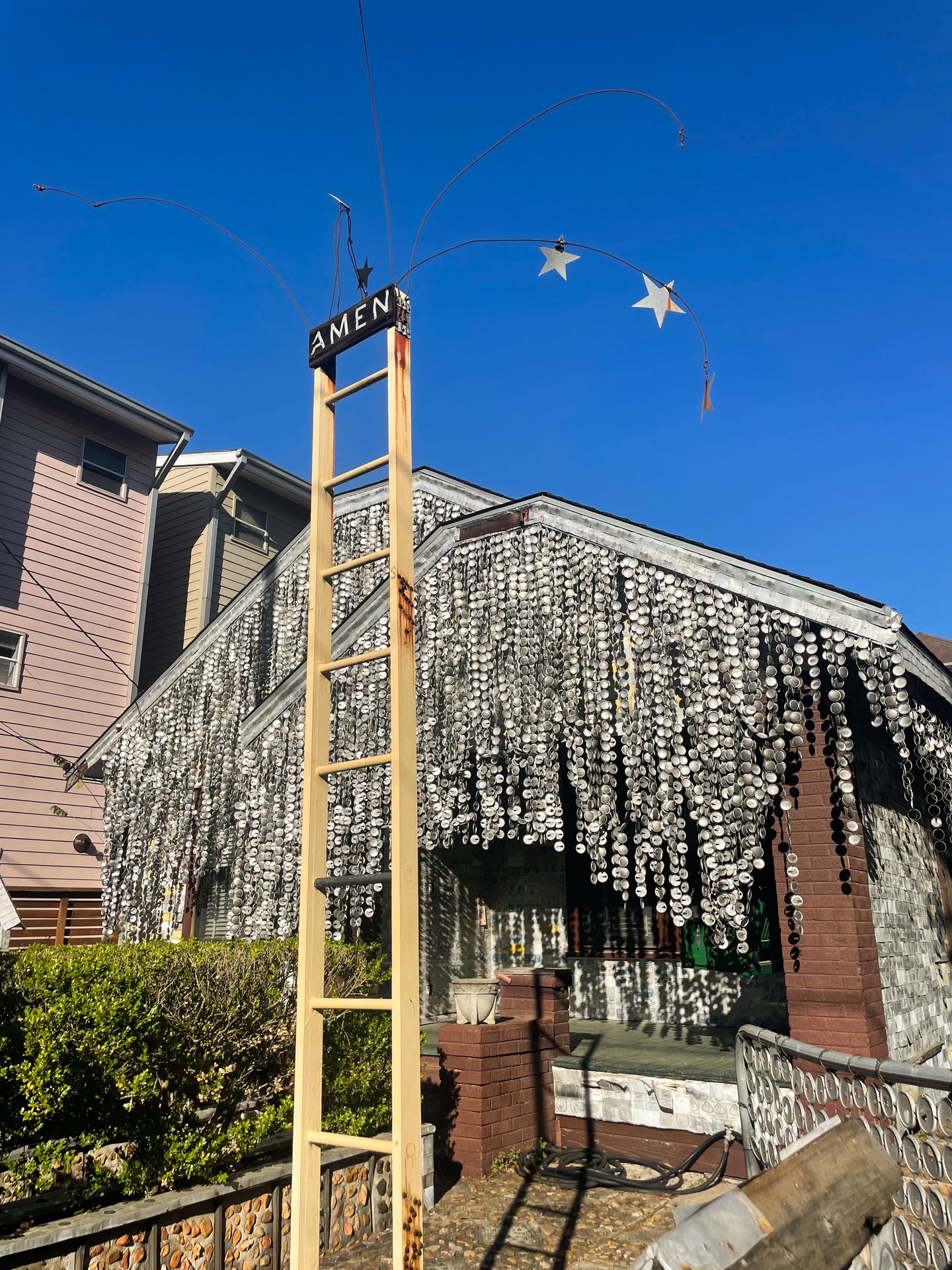 The front of the Beer Can House, where there is a tall ladder that says 'Amen' at the top