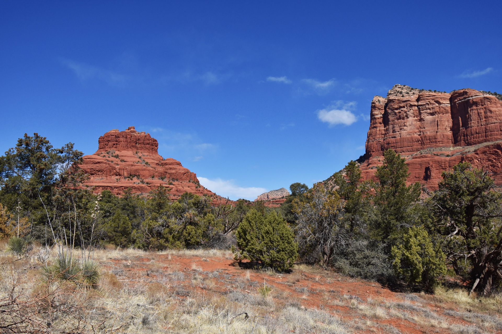 A large orange rock that resembles the shape of a bell. There is another orange mountain to the right.