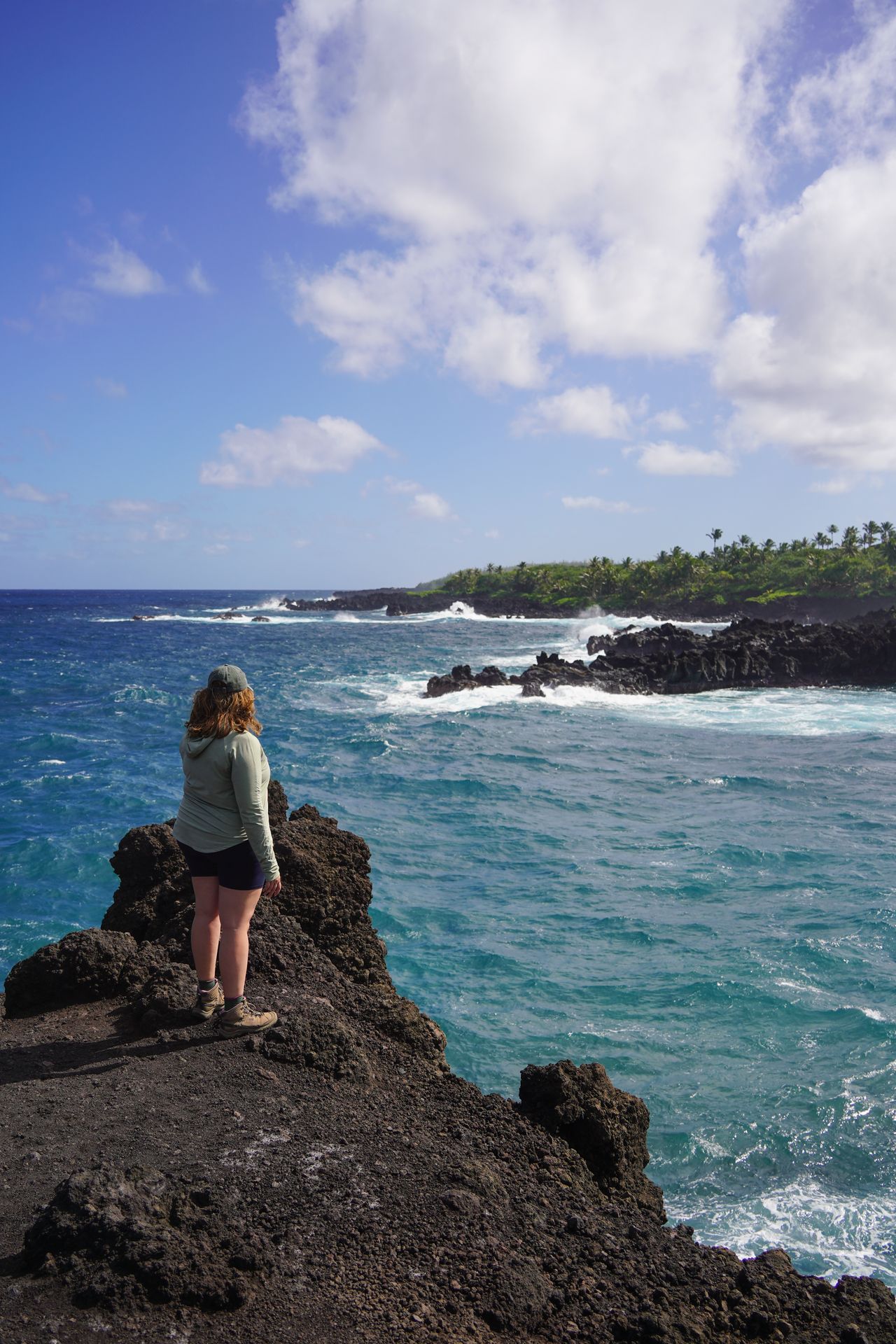 Lydia standing on black rocks up above the ocean at Wai'anapanapa State Park