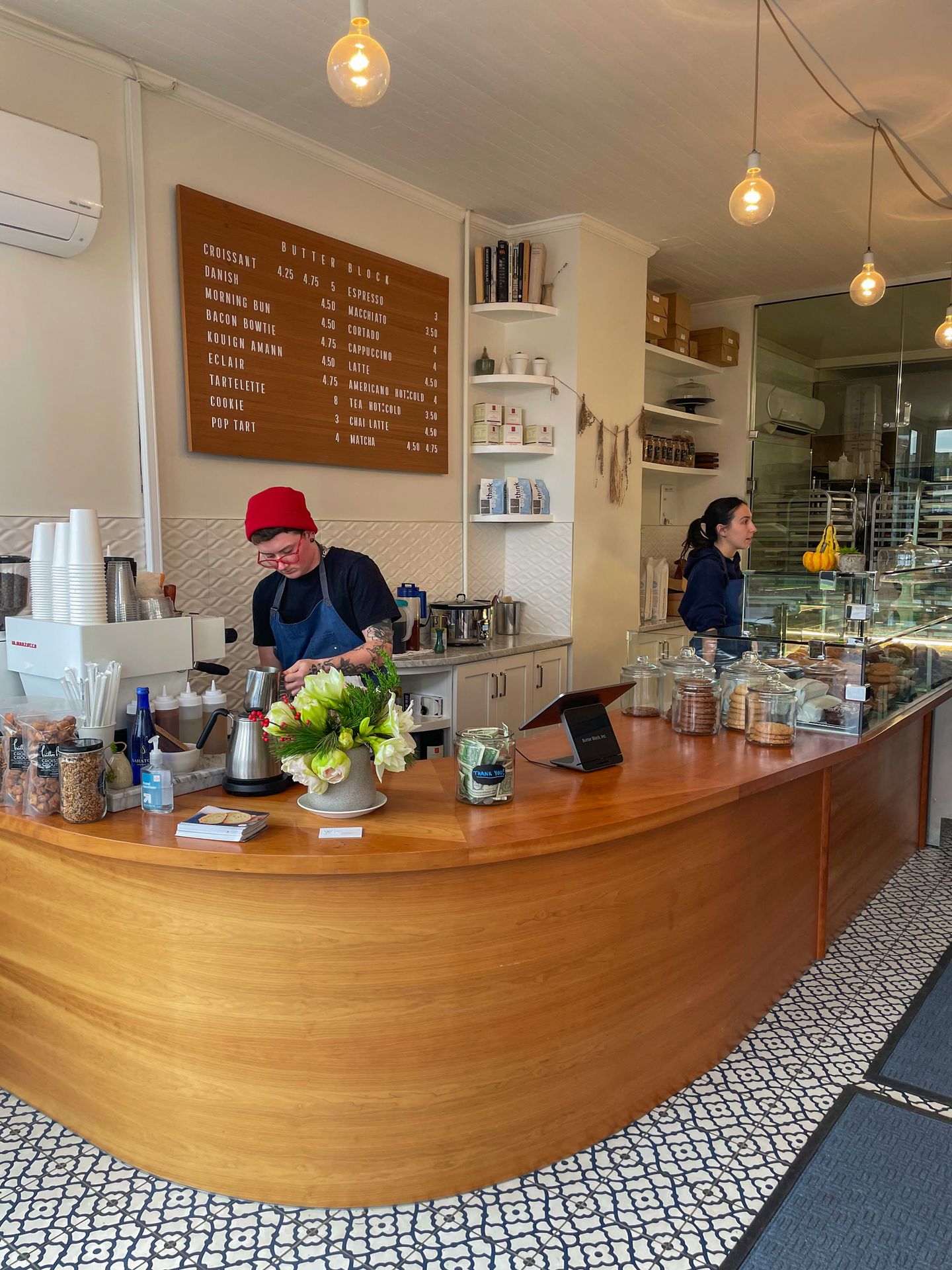 A rounded wooden counter top and a black and white tile floor inside of Butter Block.
