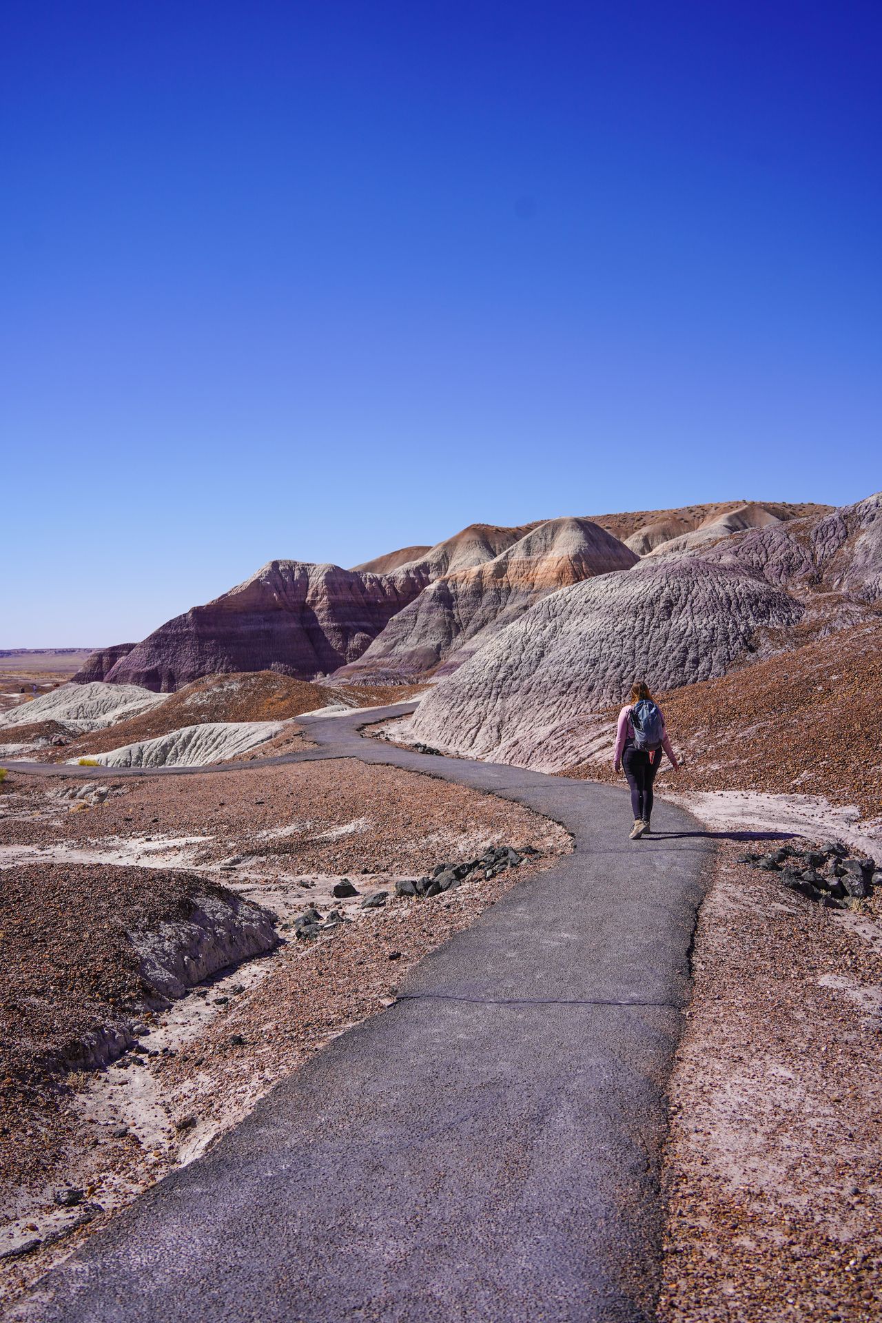Lydia hiking on a paved path surrounded by badland formations