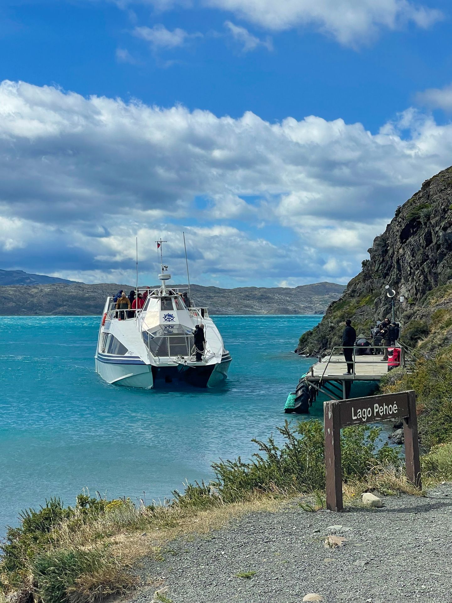 A white ferry boat on the bright blue waters of Lake Pehoe.