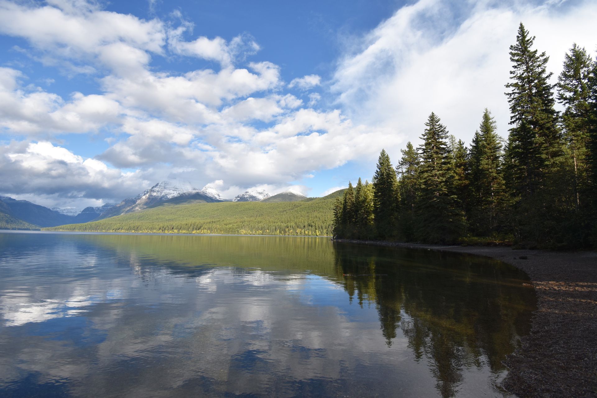 A lake with a reflection of trees and a blue sky.