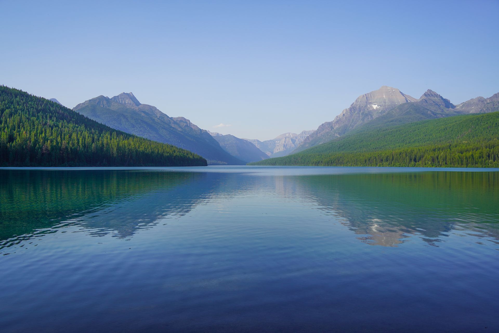 Looking across Bowman Lake to mountains and trees, which are reflected in the water