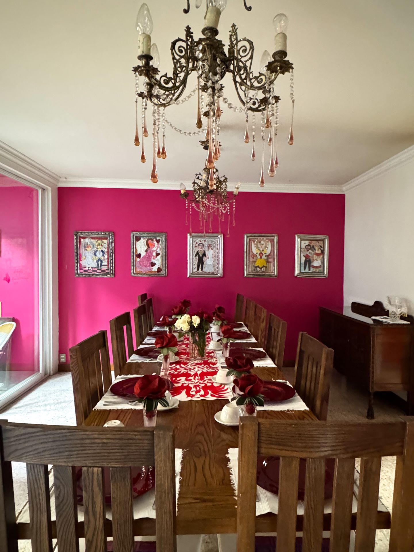 A long wooden table and a pink wall in the breakfast room of Casa de Las Bugambilias B&B