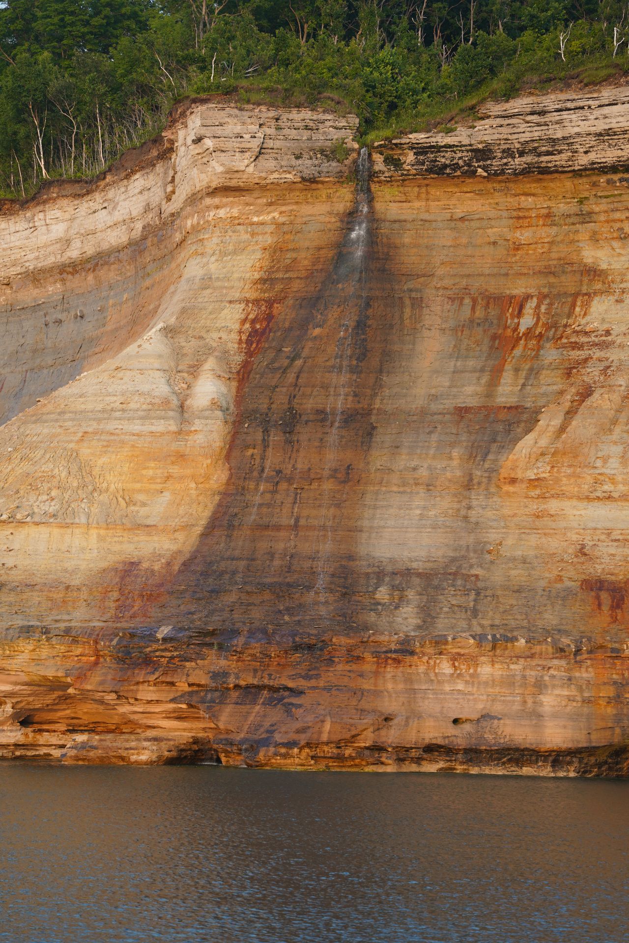 A tall waterfall coming down from the edge of a cliff.