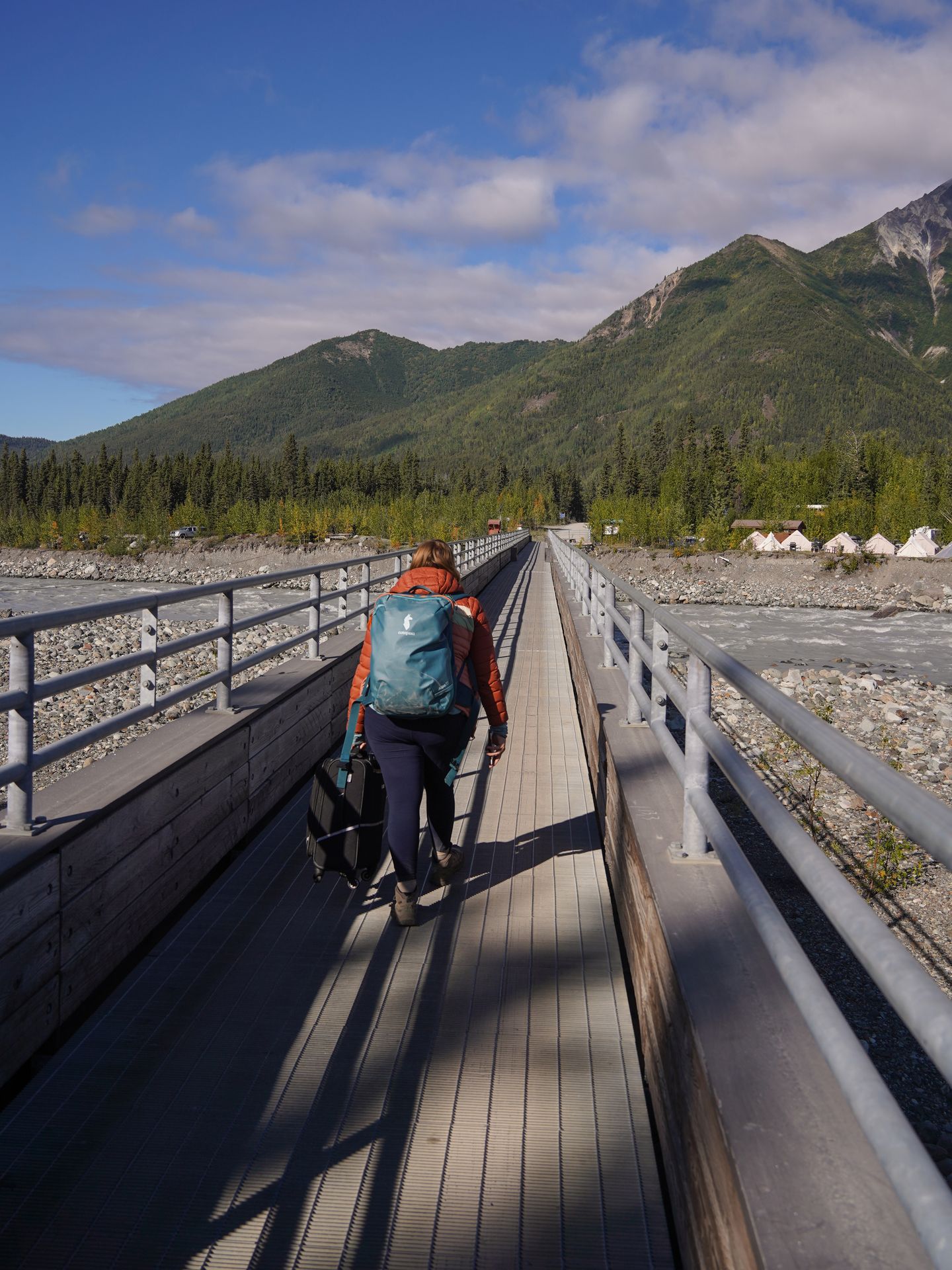 Lydia walking across the footbridge between the parking area and McCarthy